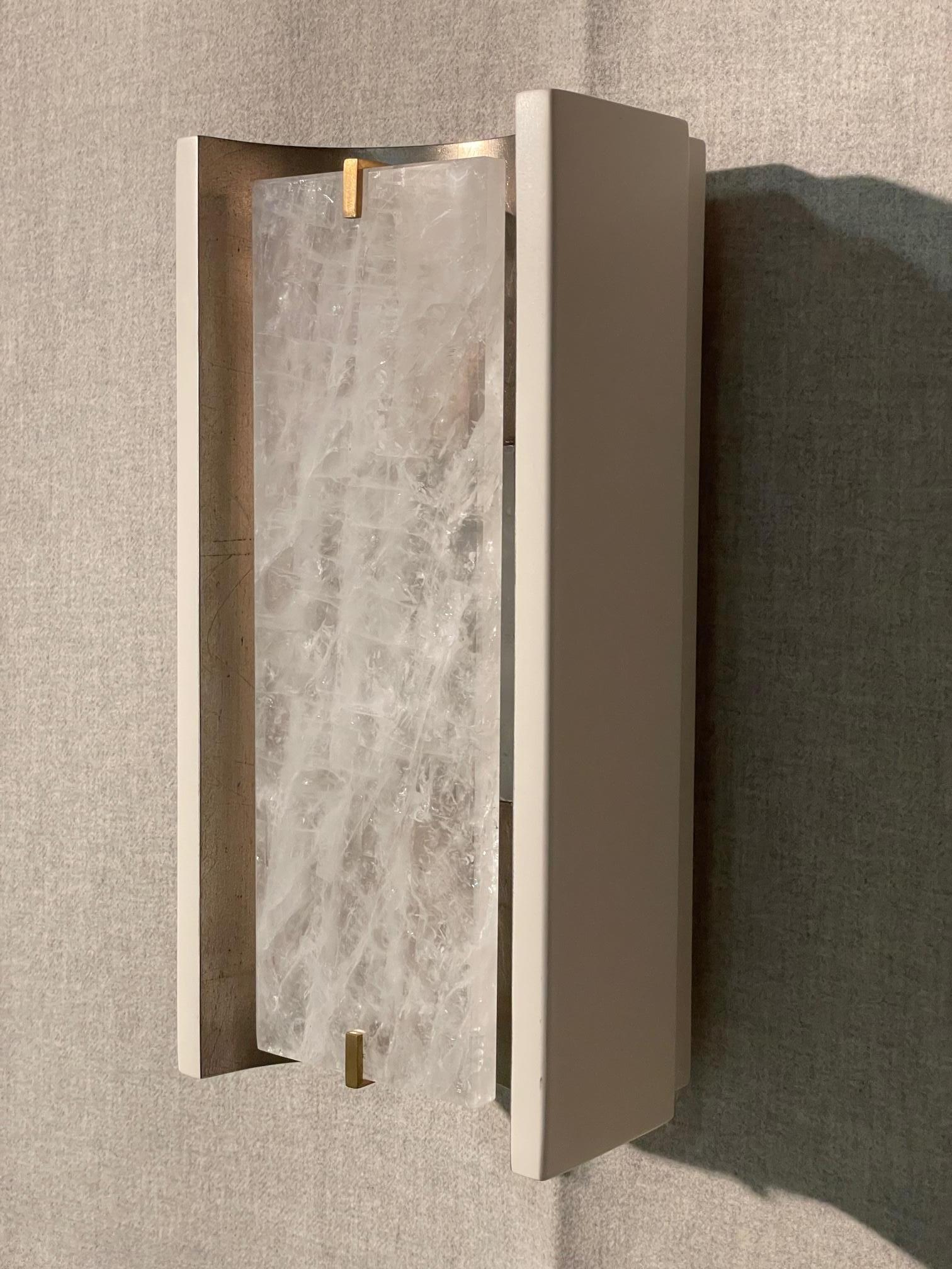 The Jean de Merry Placa de Rayon wall sconce uses two layers of rock crystal to diffuse light and create a magical, ethereal glow.  The light bounces off the Antiqued White Gold finish on the interior of the fixture while a subtle Liso satin finish