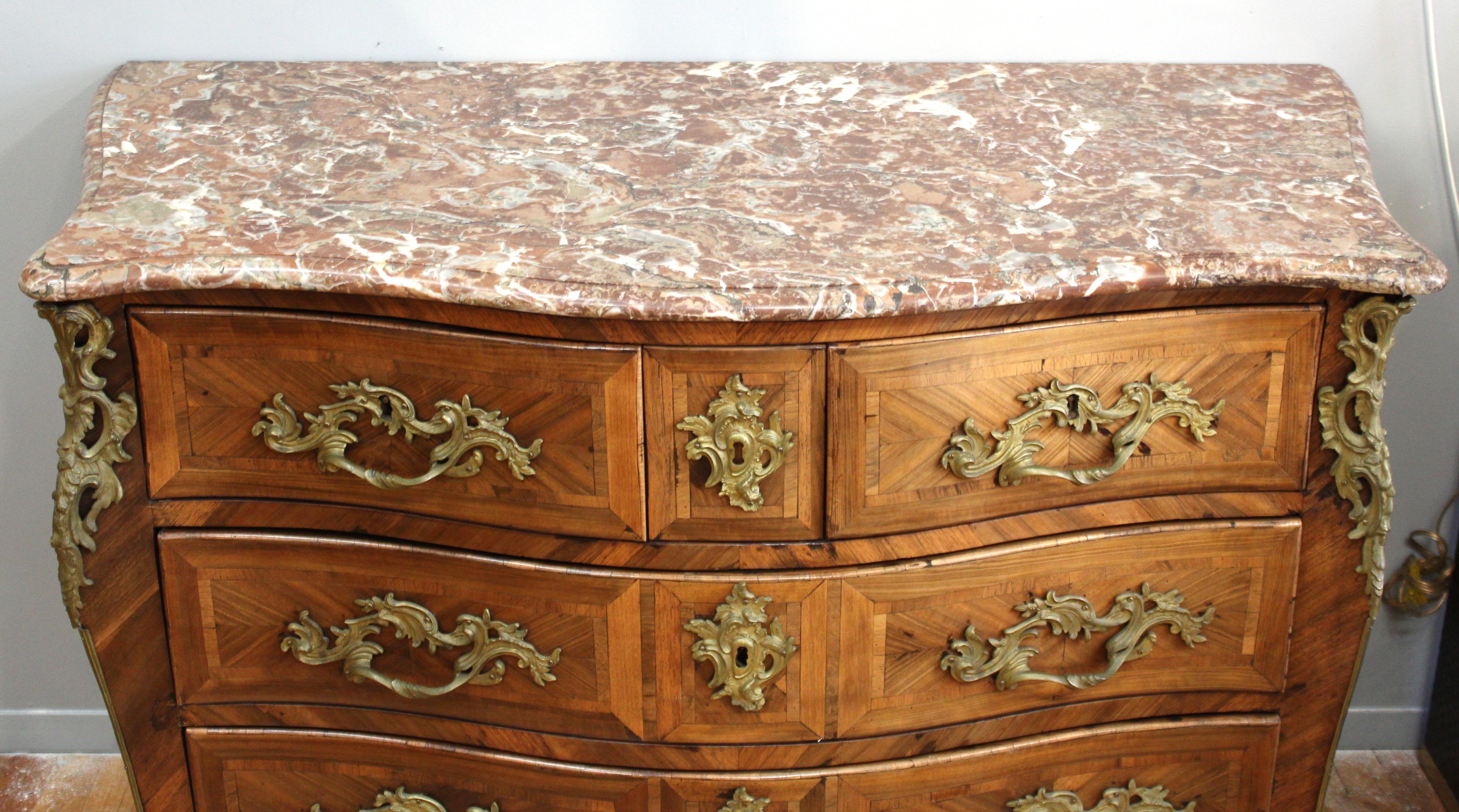 French Louis XV period commode a tombeau or serpentine chest of drawers with marble top, made by French cabinetmaker Jean Demoulin during the 1770s.
The commode is made with veneered kingwood with gilt bronze embellishments, keyholes and handles