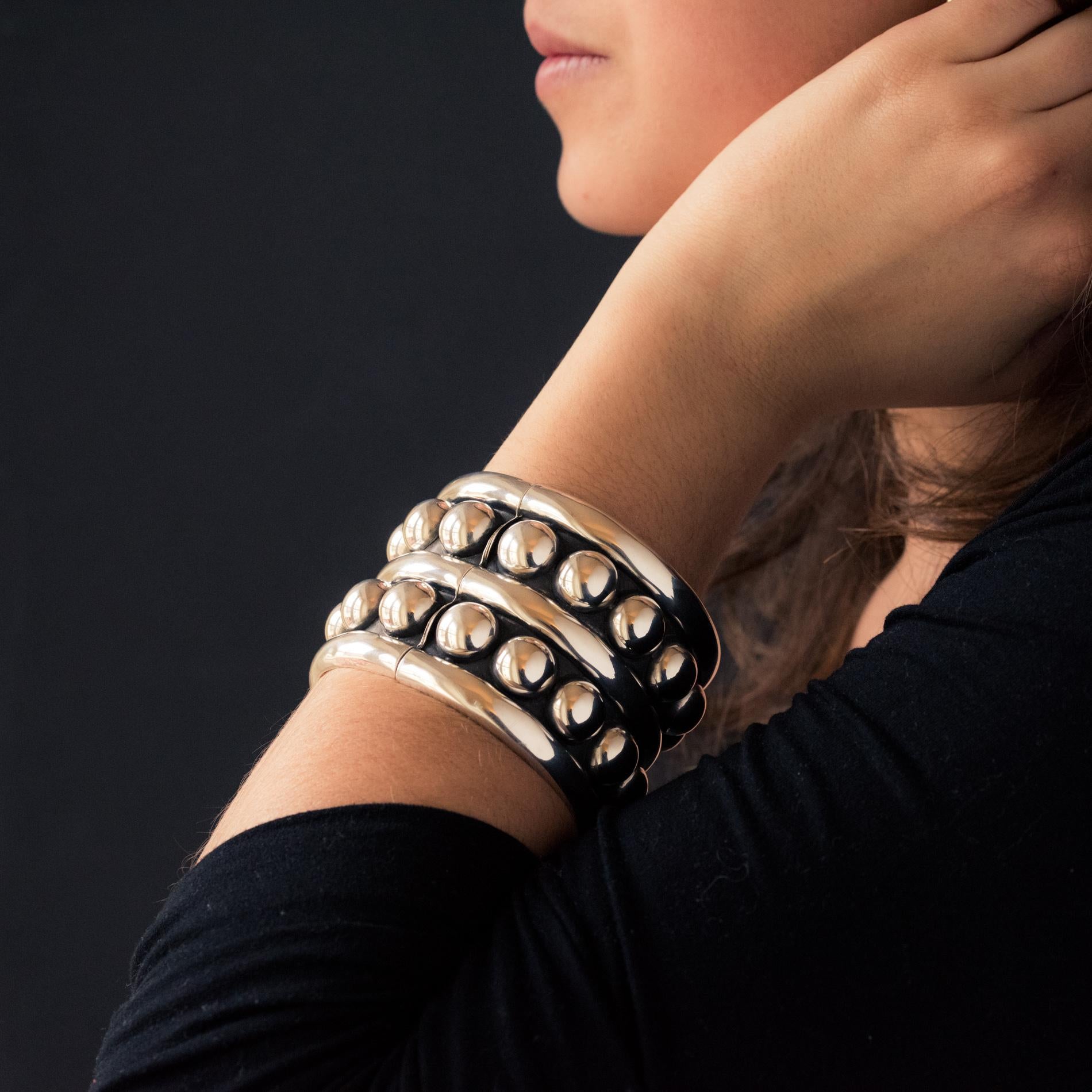 Bracelet in silver.
This sublime extra large silver cuff bracelet, consists of 2 rows of silver pearls on a gray and amati background separated and bordered by a smooth bangle. It is opening on the top by a spring hinge located at the base.
Inner