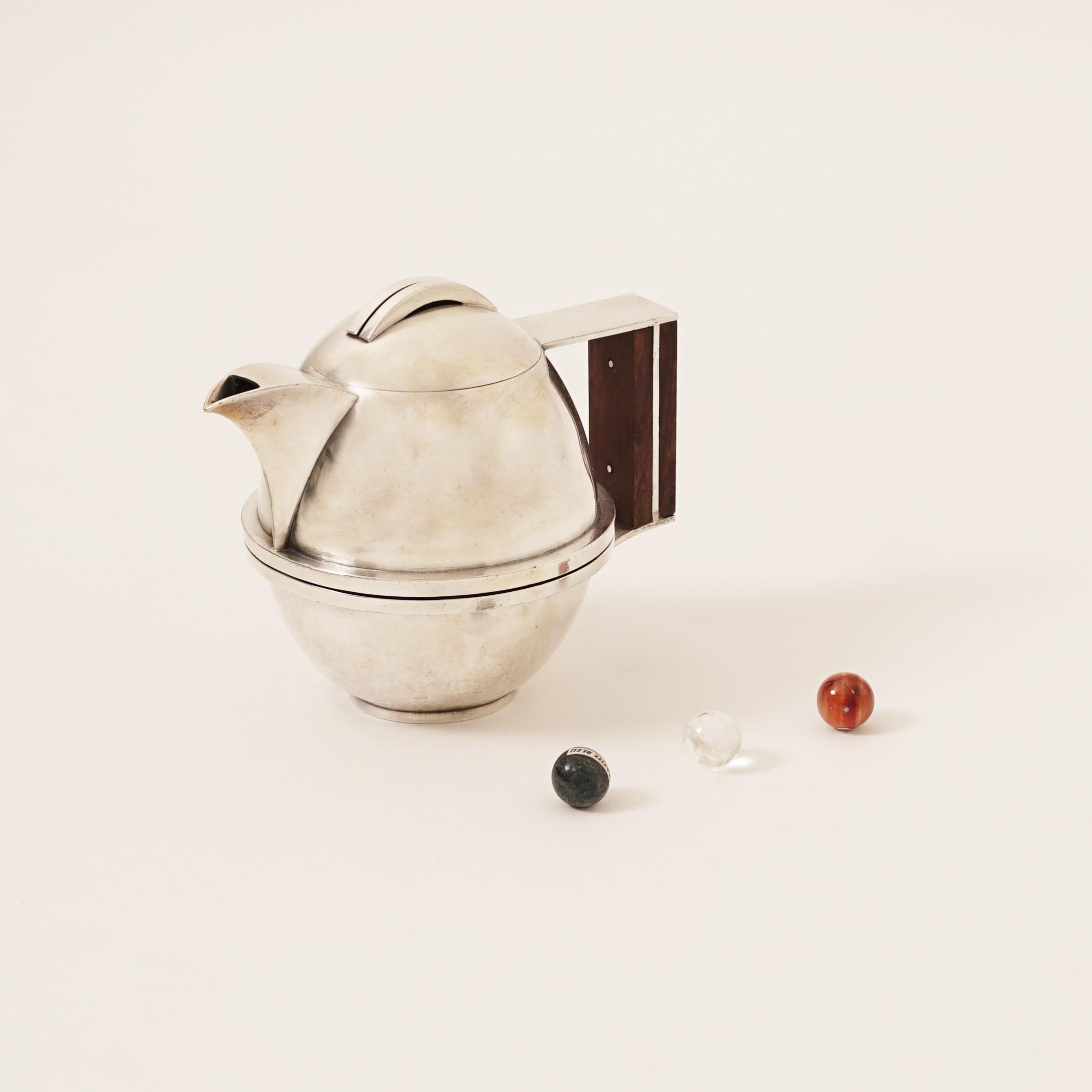 Jean Despres (1889-1980)
Tea-Pot, circa 1930
Tin, base in hammered Tin, animated with spherical stipes and angular Madagascar Ebony Wood handle. Spherical Hinged cover with two silver stripes. 
Signature incised 