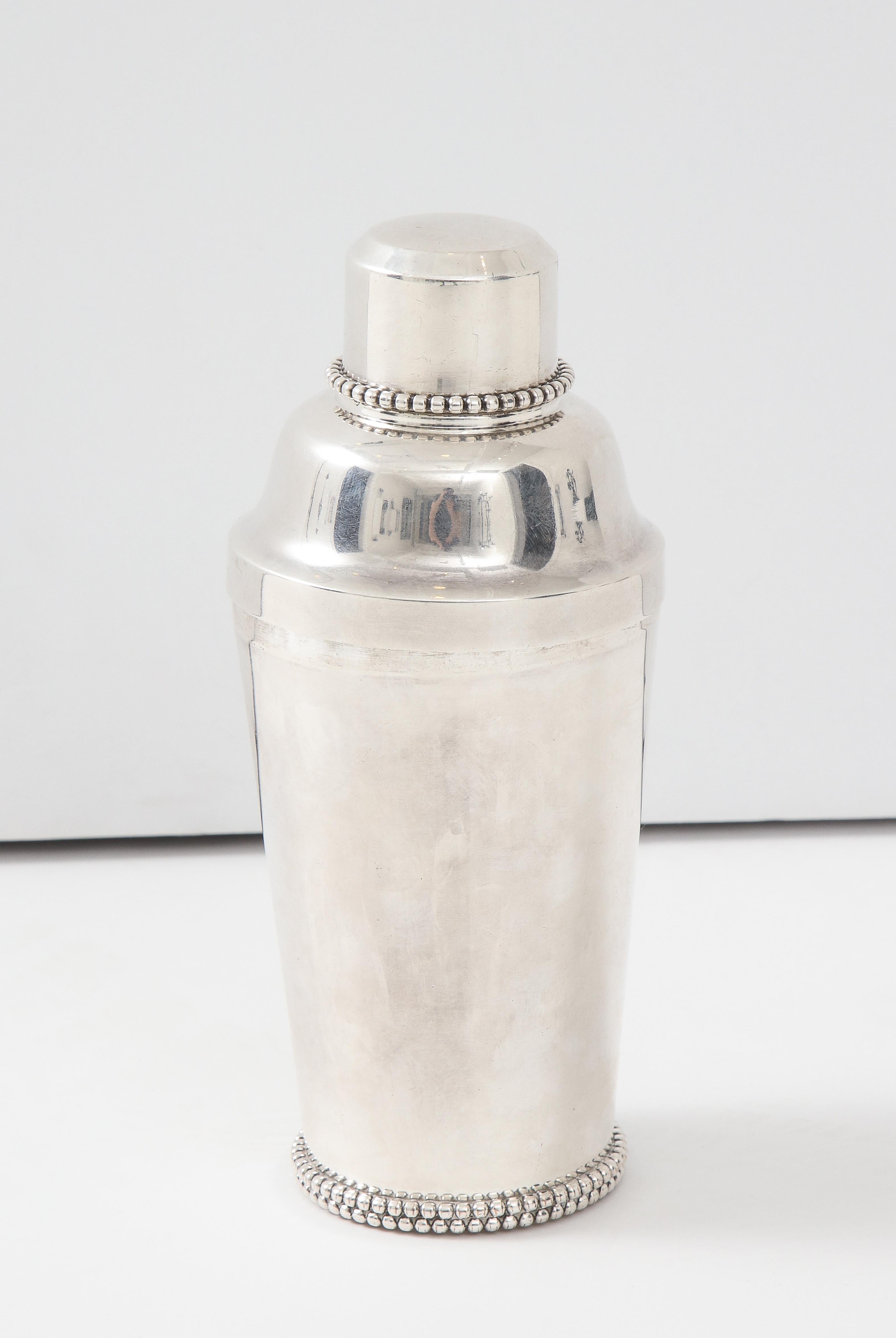 A great Jean Després beaded-plated cocktail shaker. Signed on the underside with a collar decorated with beaded design and base.