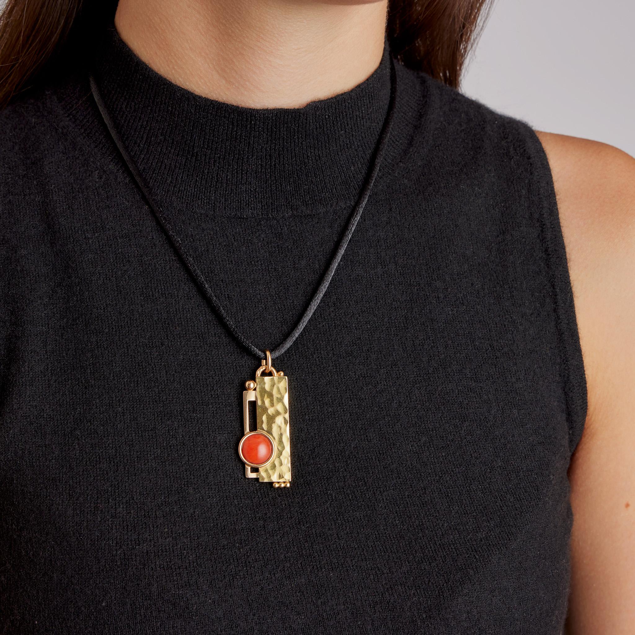 This hammered 18K gold and coral modernist pendant designed and handmade by Jean Després dates from 1930-40. It is designed as hammered rectangular plaque with an asymmetrically set coral cabochon layered over an offset partial rectangular frame,