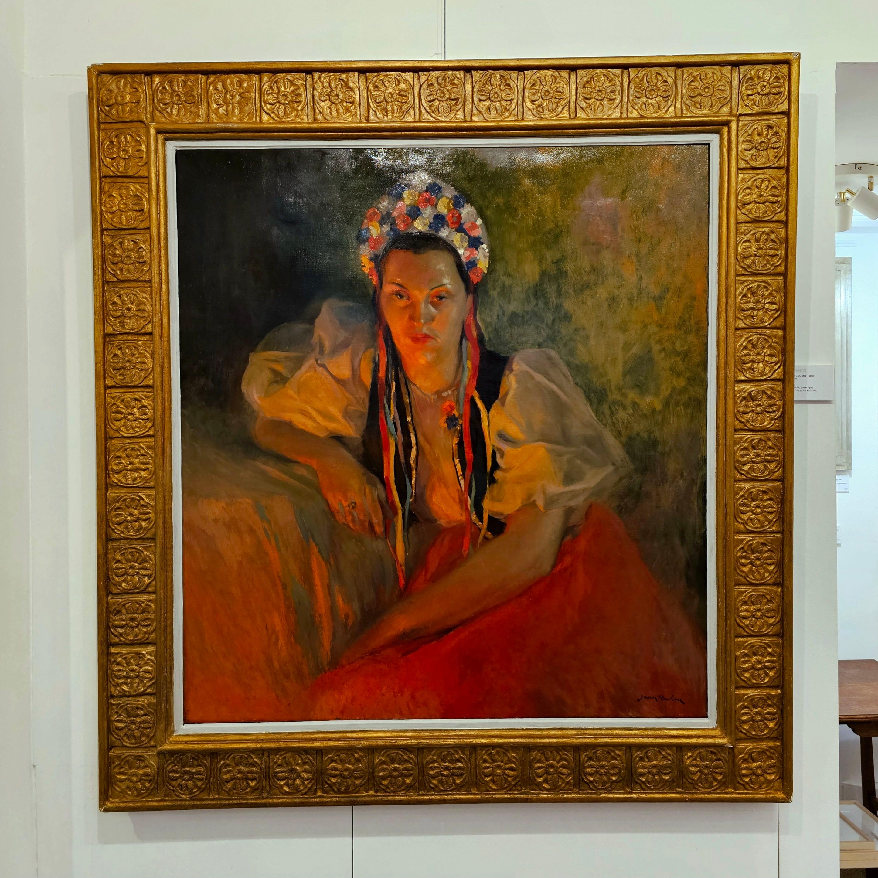 A very engaging and expansive oil painting by the Lyonnaise artist Jean Dulac.  The oil painting, painted in 1943 portrays a beautiful lady pensively looking out past the viewer while adorned in traditional French costume. The use of red and ochre