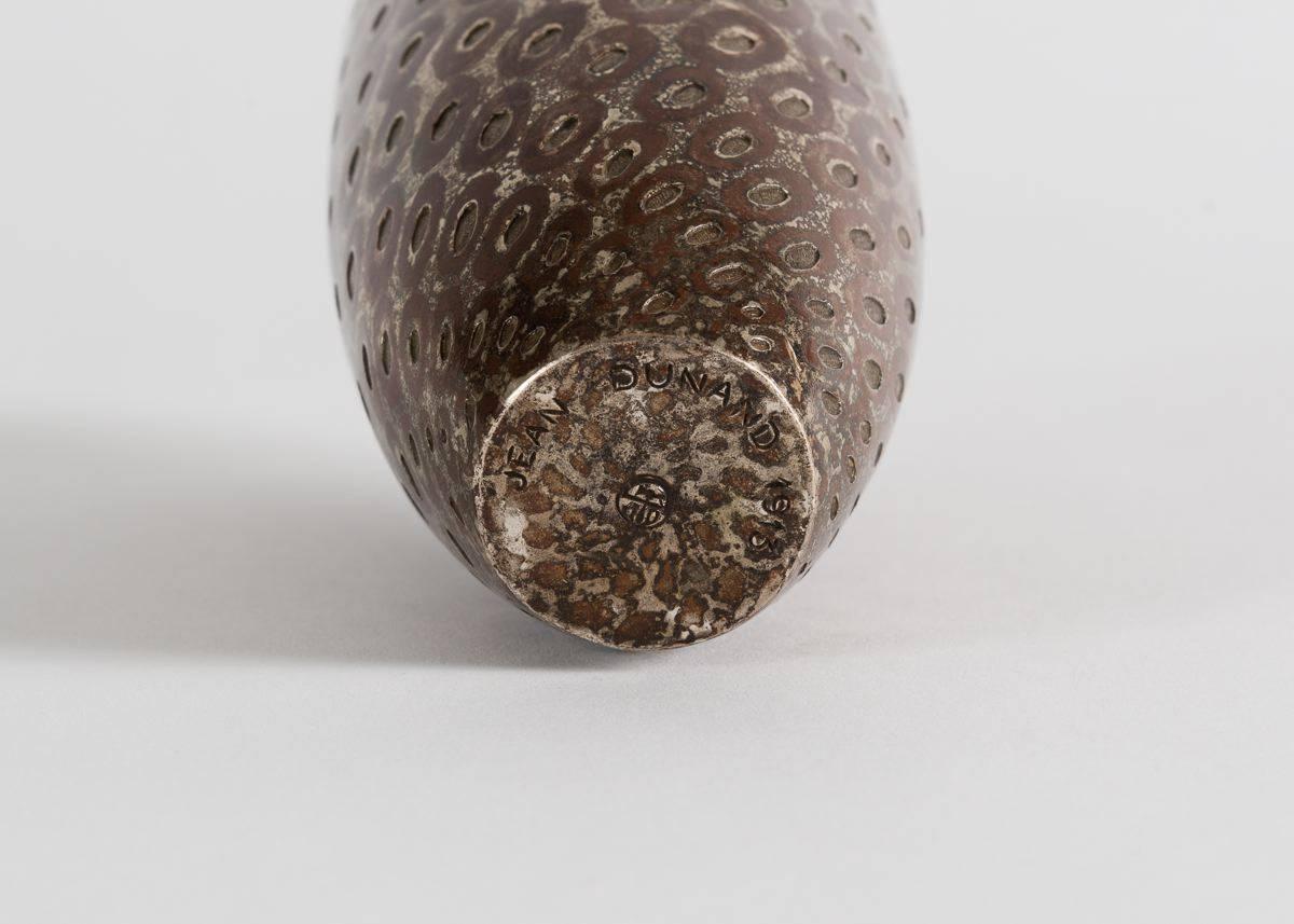 A remarkable vase dating from the very beginning of the Art Deco period, this piece, by the inimitable Jean Dunand, has a surface colored and perforated so as to appear like the scales of a fish or a reptile--its genius that its surface evokes both