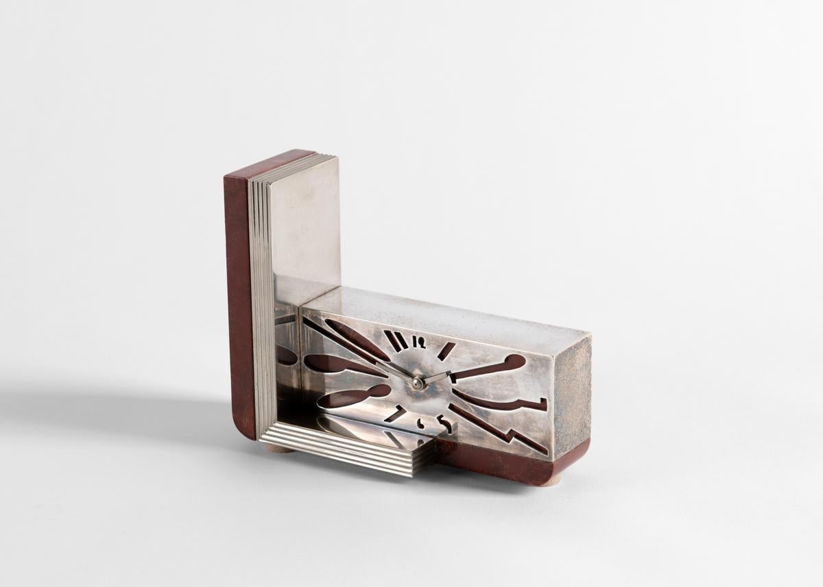 With this elegant Art Deco desk clock the eminent French designer Jean E. Puiforcat created a charming juxtaposition of aesthetic weight with levity, its dignified rectilinear marble border cut off with rakish asymmetry, its nickel-plated bronze