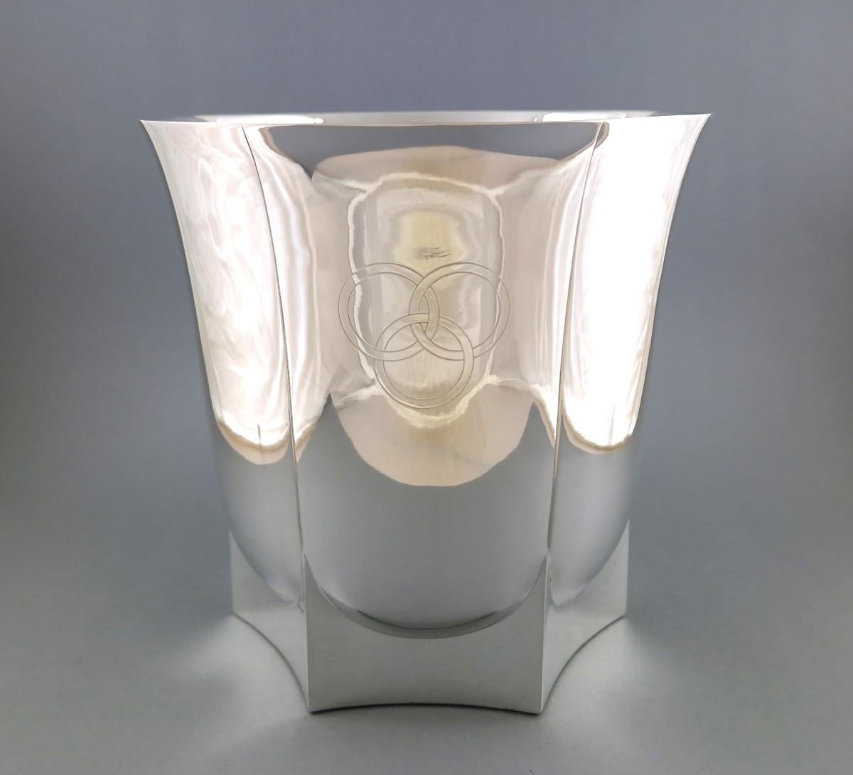 Champagnerkübel aus Sterlingsilber im Art Deco-Stil 

Er hat eine kegelstumpfförmige Form und steht auf einem getäfelten Sockel mit gebogenen Ecken, wobei die Seiten in vertikalen Feldern nach oben verlaufen. Der obere Teil ist leicht ausgestellt.