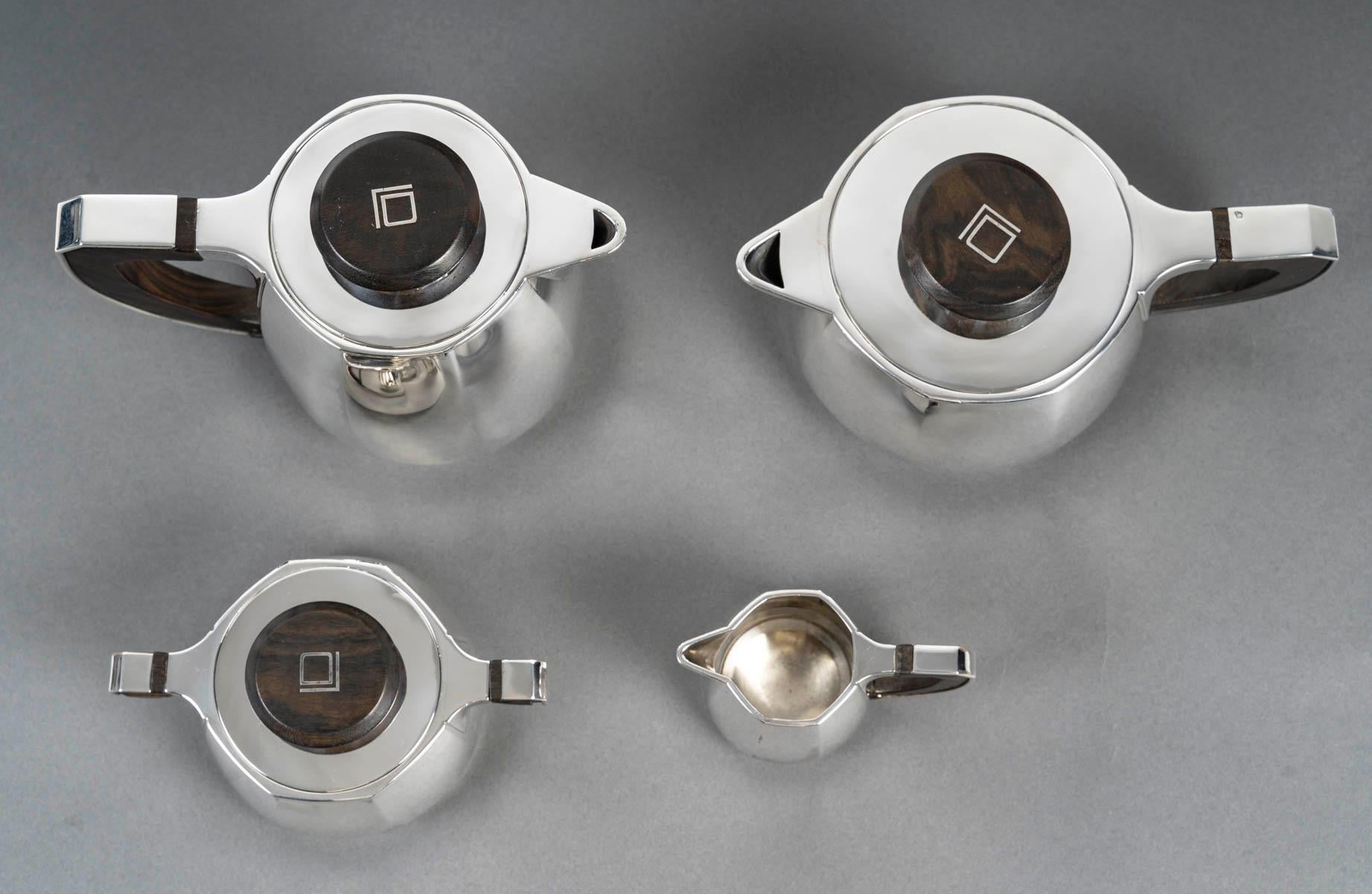 Set da tè/caffè in argento massiccio con design a taglio, manici in argento e impugnature stilizzate in legno e argento, comprendente caffettiera, teiera, lattiera e zuccheriera coperta. Monogram LD.

Dimensioni: Caffettiera: 20.5cm x 13cm x 15 cm
