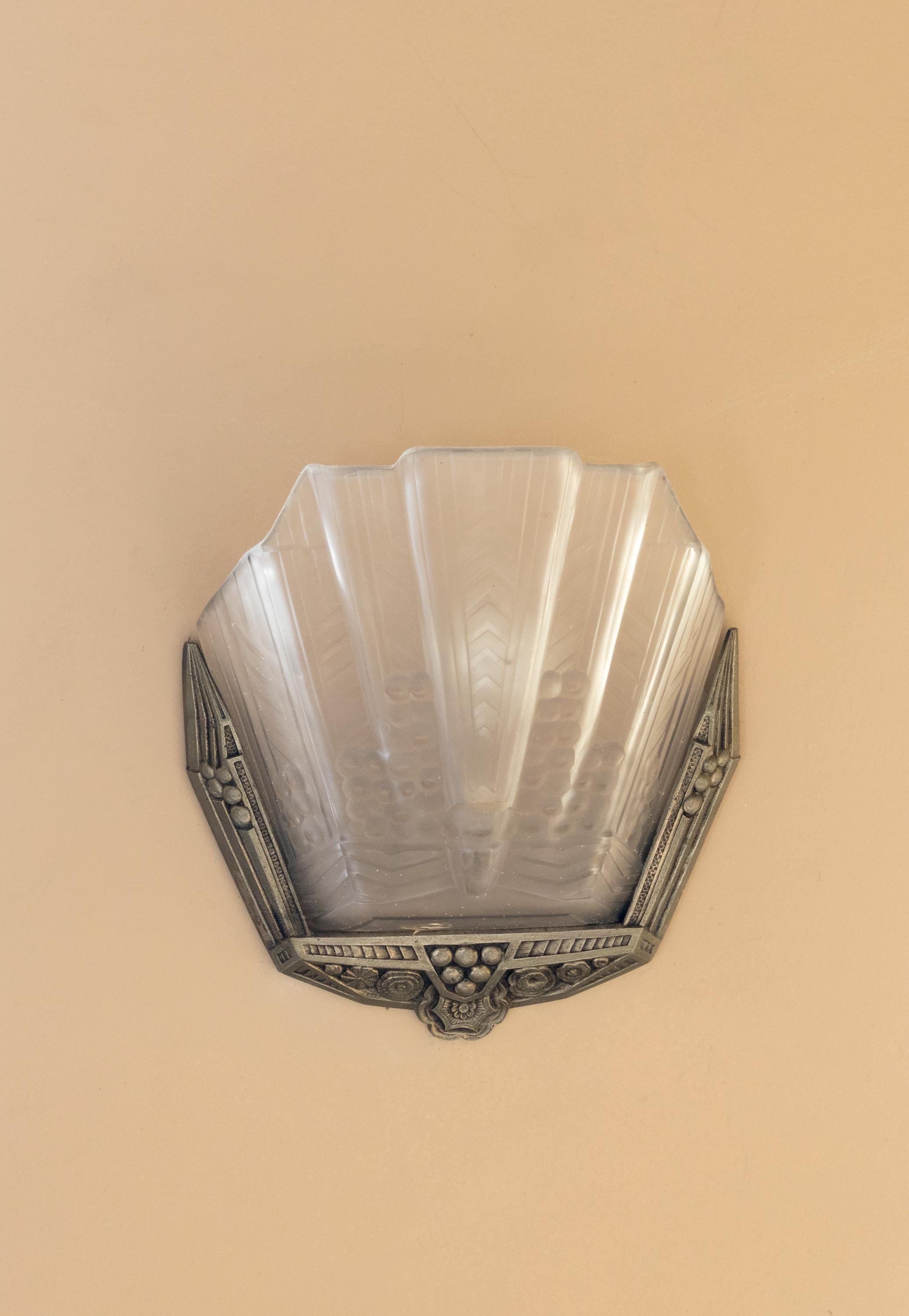 French Art Deco wall sconce by Jean GAUTHIER (Ezanville, Paris), France, 1920s in solid nickel-plated brass holding a frosted pressed glass panel. Unsigned. 
 
Jean Gauthier had his first workshop at 12-14 rue Jean Robert in Paris and later expended