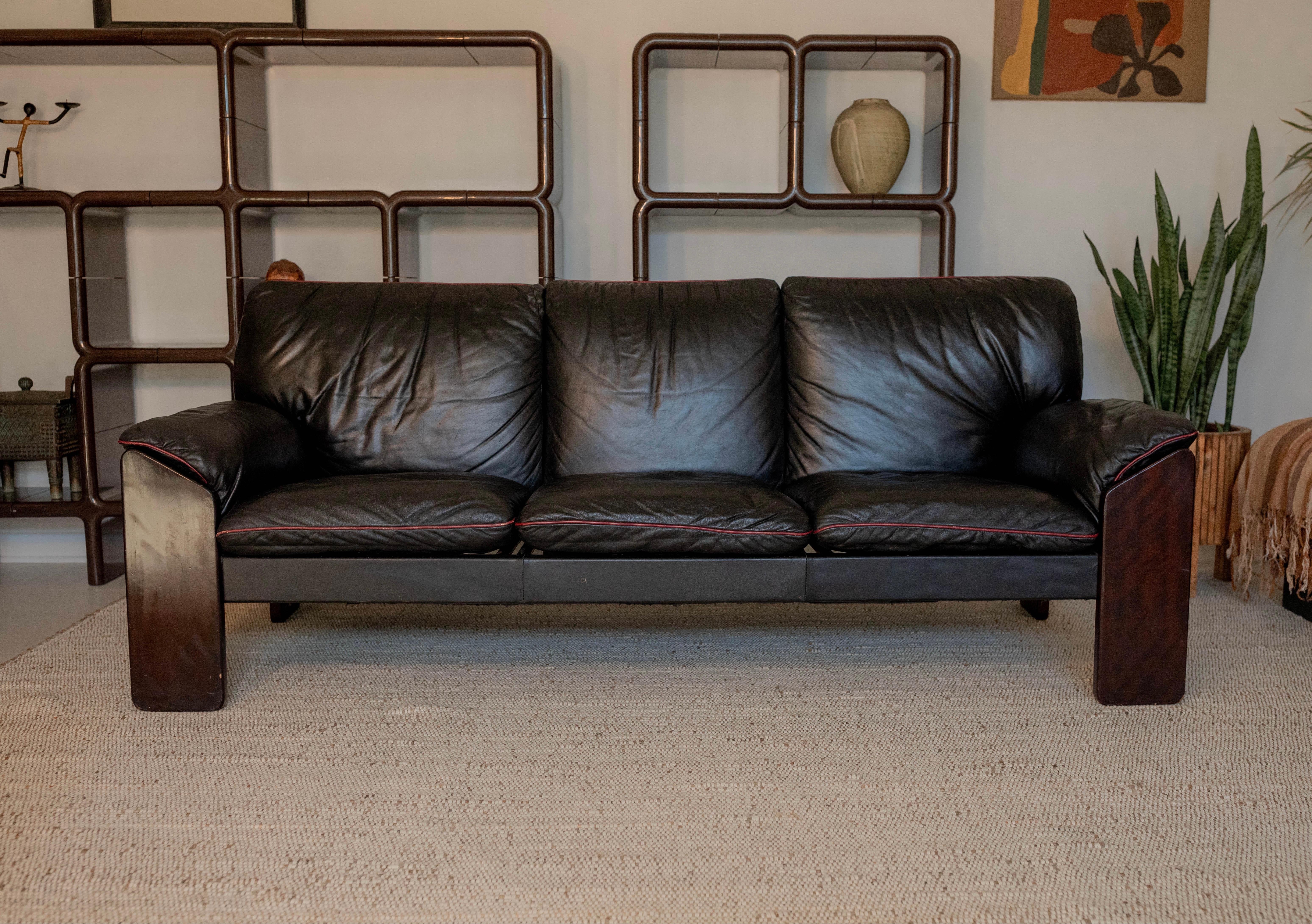 This rare Brazilian Modern sofa is by Jean Gillon for Probel and features a gorgeous Brazilian Jacaranda frame with very-comfortable black leather cushions and arms with contrasting sporty red piping. Signed with a Probel Made in Brazil label.