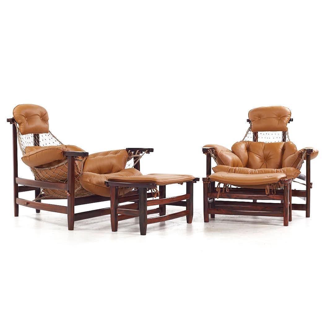 Jean Gillon Jangada Mid Century Brazilian Rosewood and Leather Lounge Chairs with Ottomans - Pair

The chair measures: 40 wide x 41 deep x 36.5 high, with a seat height of 14.5 inches and arm height/chair clearance of 22 inches
(Exact measurements
