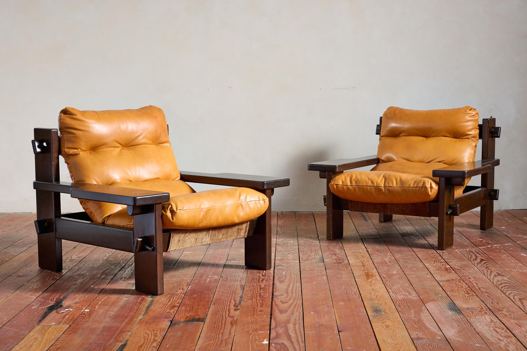 Fantastic large scale pair of Paddle leather armchairs by Jean Gillon - Brazil, circa 1960s
Dark wood frame with Wide paddle shaped arms and unique large nut & bolt joinery. 
Buttery leather that is original in caramel color 
Great pair!