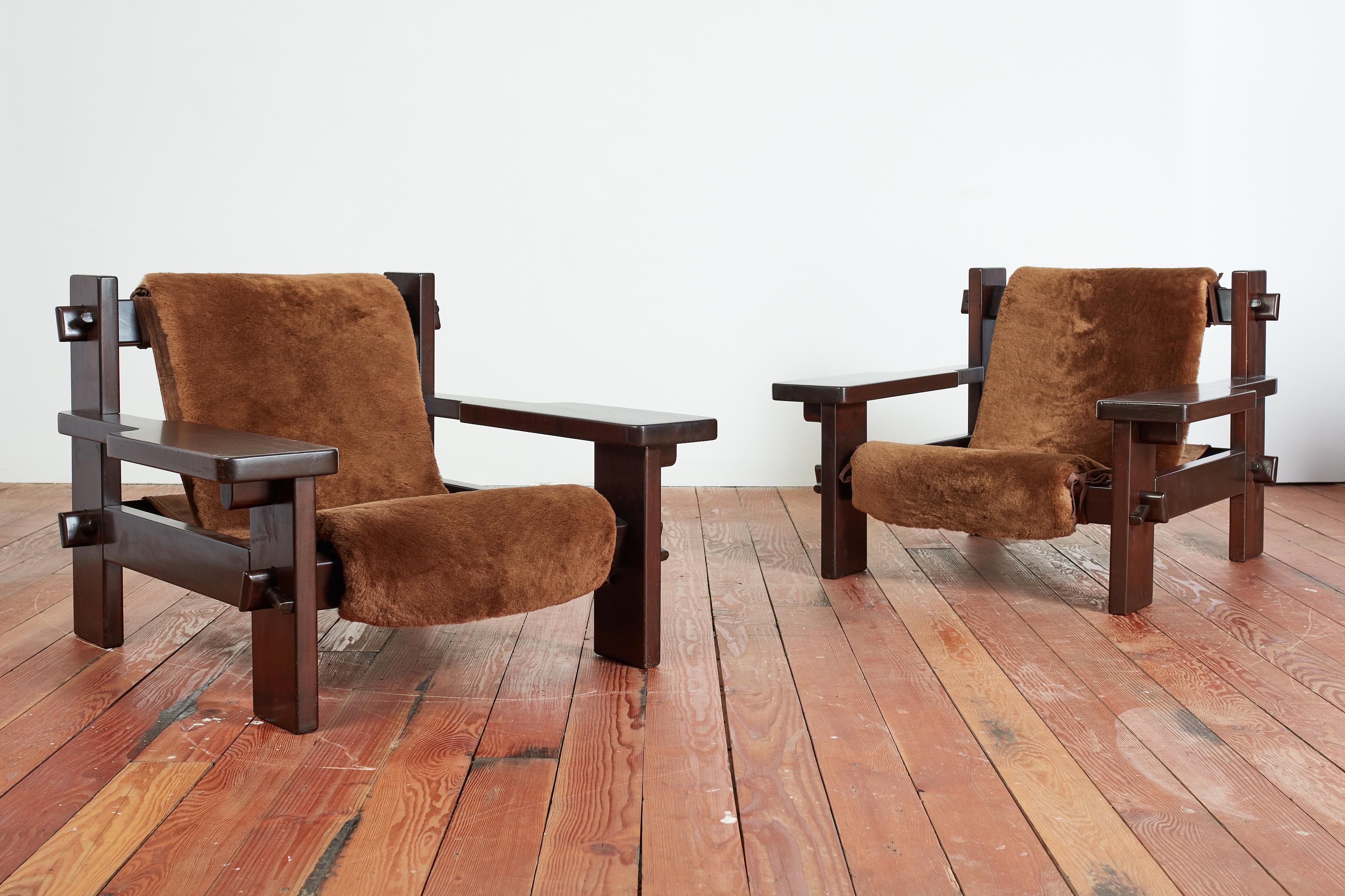 Fantastic large scale pair of Paddle Armchairs by  Jean Gillon for Probel.  Brazil, circa 1970s 
Dark wood frame with Wide paddle shaped arms and unique large nut & bolt joinery. 
Sling seat with newly upholstered in dark chocolate brown shearling
