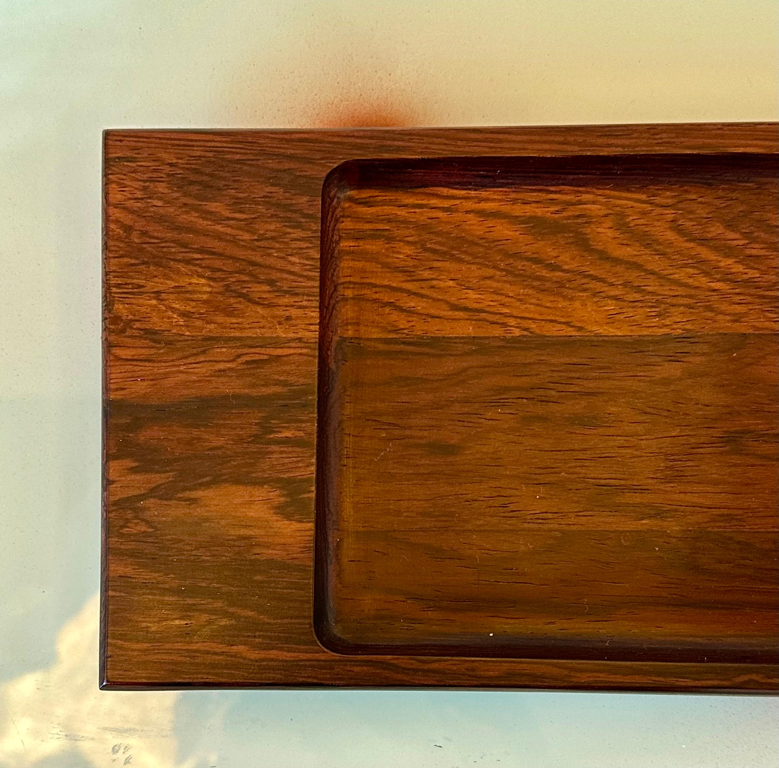 Dieses rechteckige Tablett des Modells 304 von Jean Gillon stammt aus der Zeit um 1960. Die aus Massivholz gefertigte Platte hat die Maße 2 x 35 x 12 Zentimeter. Die Authentizität dieser Kreation wird durch das Vorhandensein des Wood Art 1/304