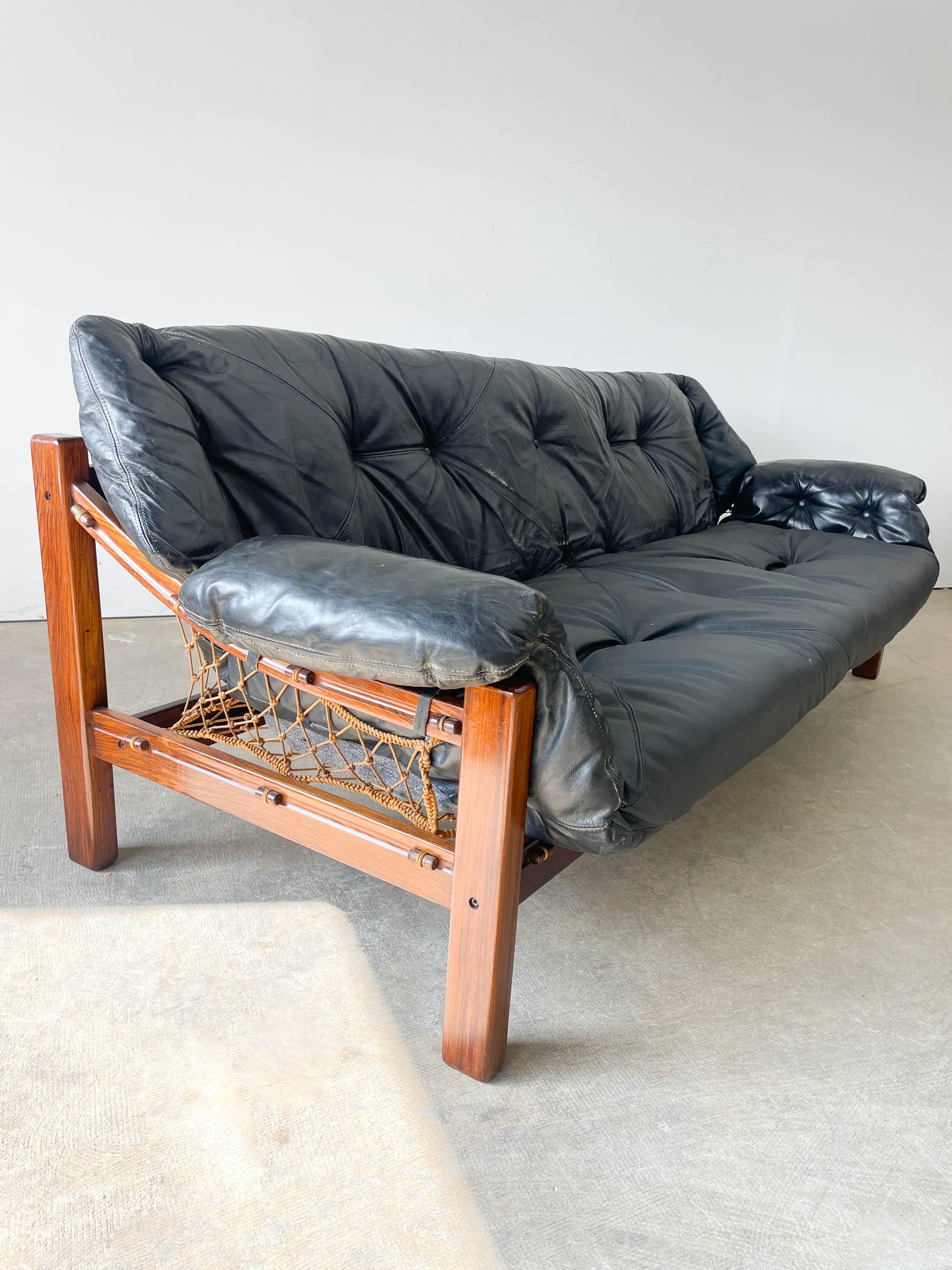 Designed by Jean Gillion for Italma of Brazil in the 1970s, this 'Tijuca'' sofa features a thick leather cushion supported by an intricately woven string hammock on a solid Brazilian Rosewood Frame. The suspension makes the seat incredibly