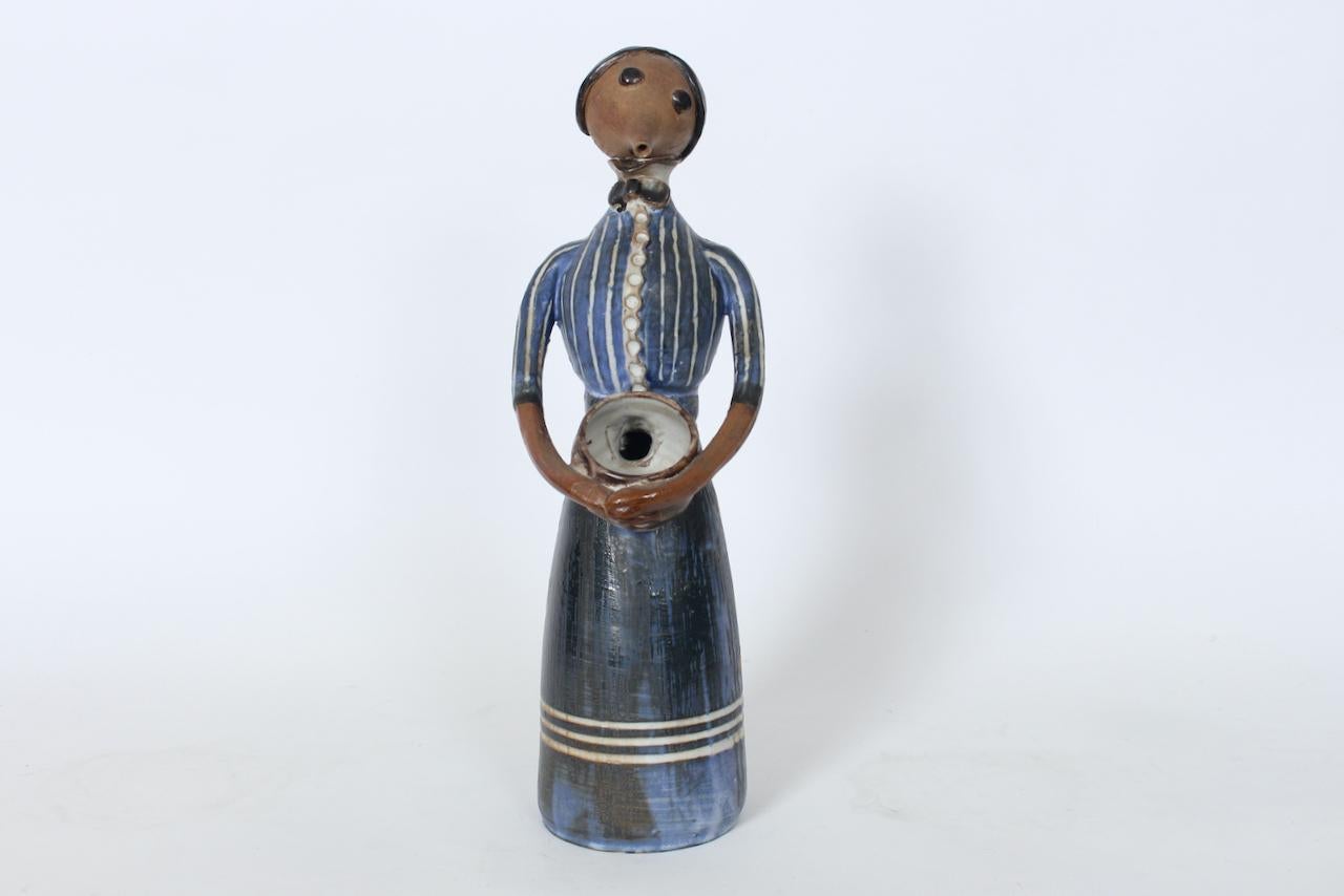 Jean Hastings Clothed Figurative Art Studio Glazed Ceramic Sculpture. Vase. Featuring hand constructed figurative form elements from potters wheel with separate hand built and applied pieces including, Head, Eyes, Torso, Hands, and Basket. With Blue