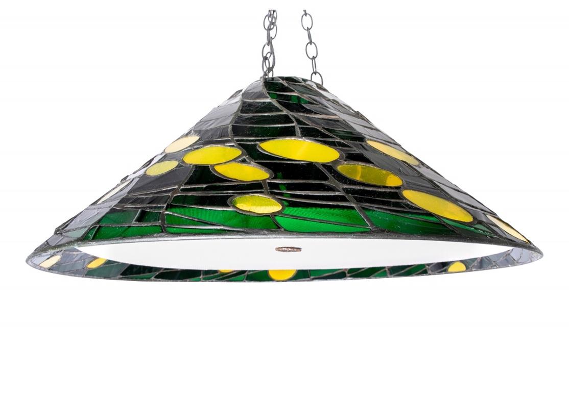 A conical leaded fixture in green glass with yellow spheres in a scattered design. With a white metal mesh liner on the base with metal attachment
The noted glass artisan was a Pioneer in the use of faceted glass in stained glass in the 1960s. His