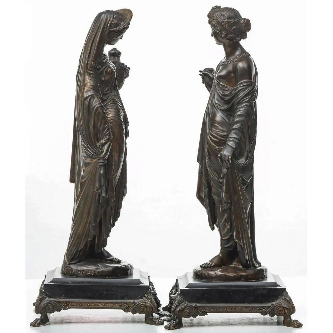 La coppia di figure in bronzo fuso esposte su basi di ardesia abbinate con fogliame inciso e dorato in una cornice di bronzo neoclassica con maschera femminile e sollevata su piedi a zampa; la figura che regge un recipiente è una raffigurazione di