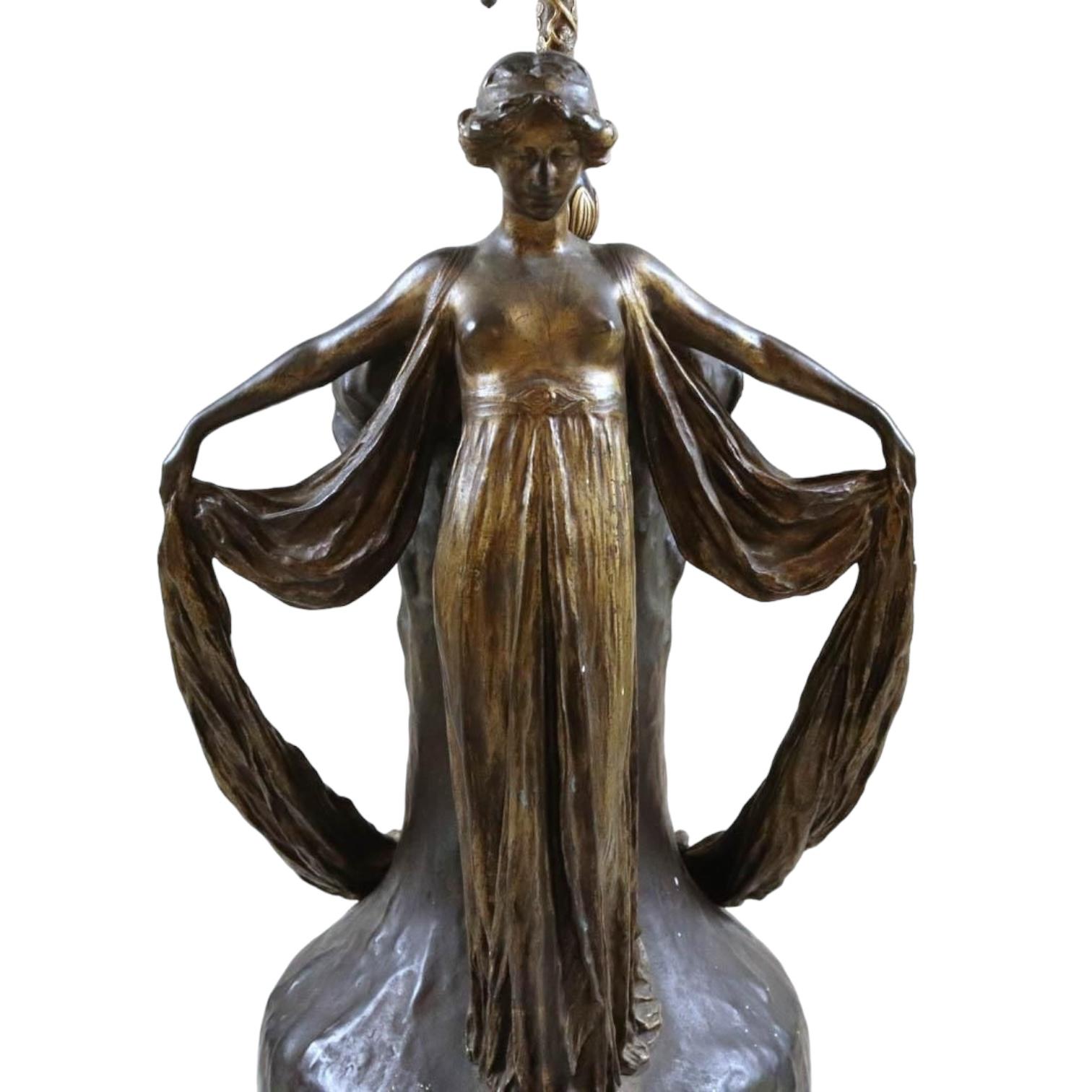 Nuestro antiguo jarrón de bronce según el modelo original de Jeanne Jozon (1868-1946) se conoce como La Danse (La Danza), y se montó como lámpara de mesa en el momento de su fundición o poco después.  Se dice que esta obra de Jozon representa o se