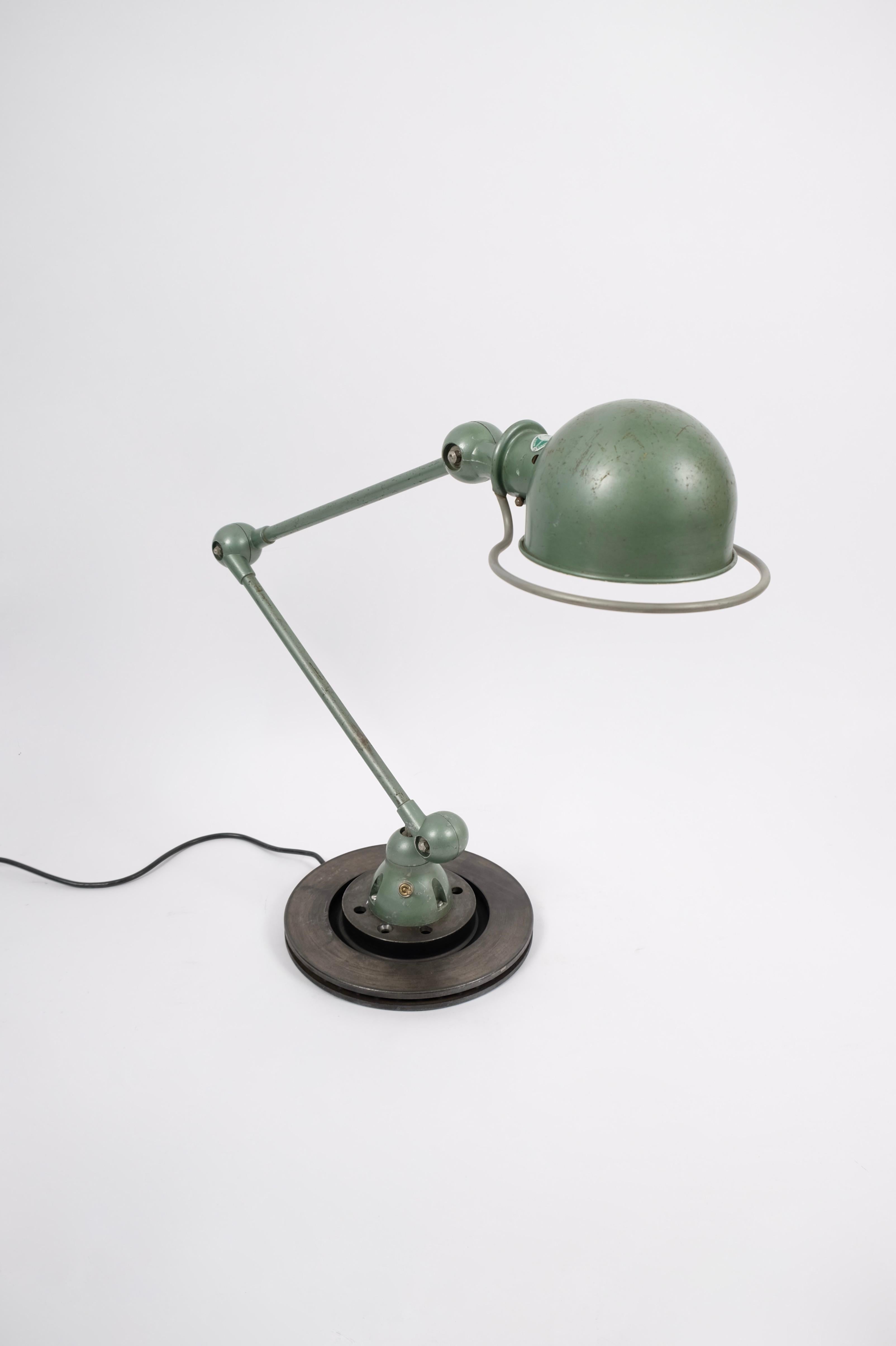 Beautiful working lamp in original Vespa green lacquer.
Features a blue metal plate from the maker.
Each arm measures 45 cm and can be moved horizontally.
The shade/head pivots 360 degrees around the shade holder.
Mounted on 5 Kilo brake disc to