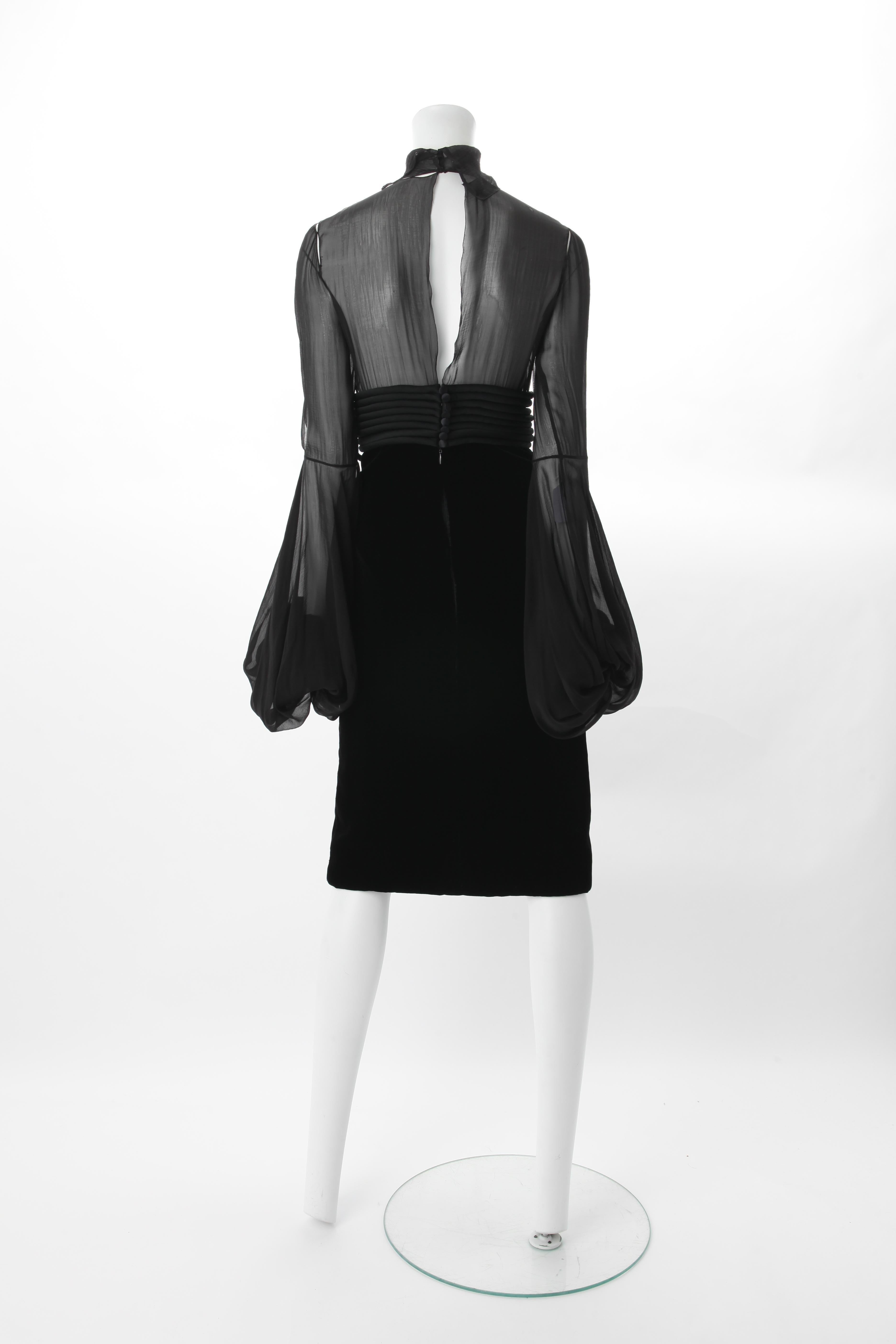 Jean-Louis Scherrer by Stephane Rolland Black Dress w/ Rouleux Waistband, A/W 2003.
Knee length black dress with velvet skirt and turtleneck sheer silk bodice featuring long bishop sleeves. Dress also features a Rouleux high waistband and bow tie