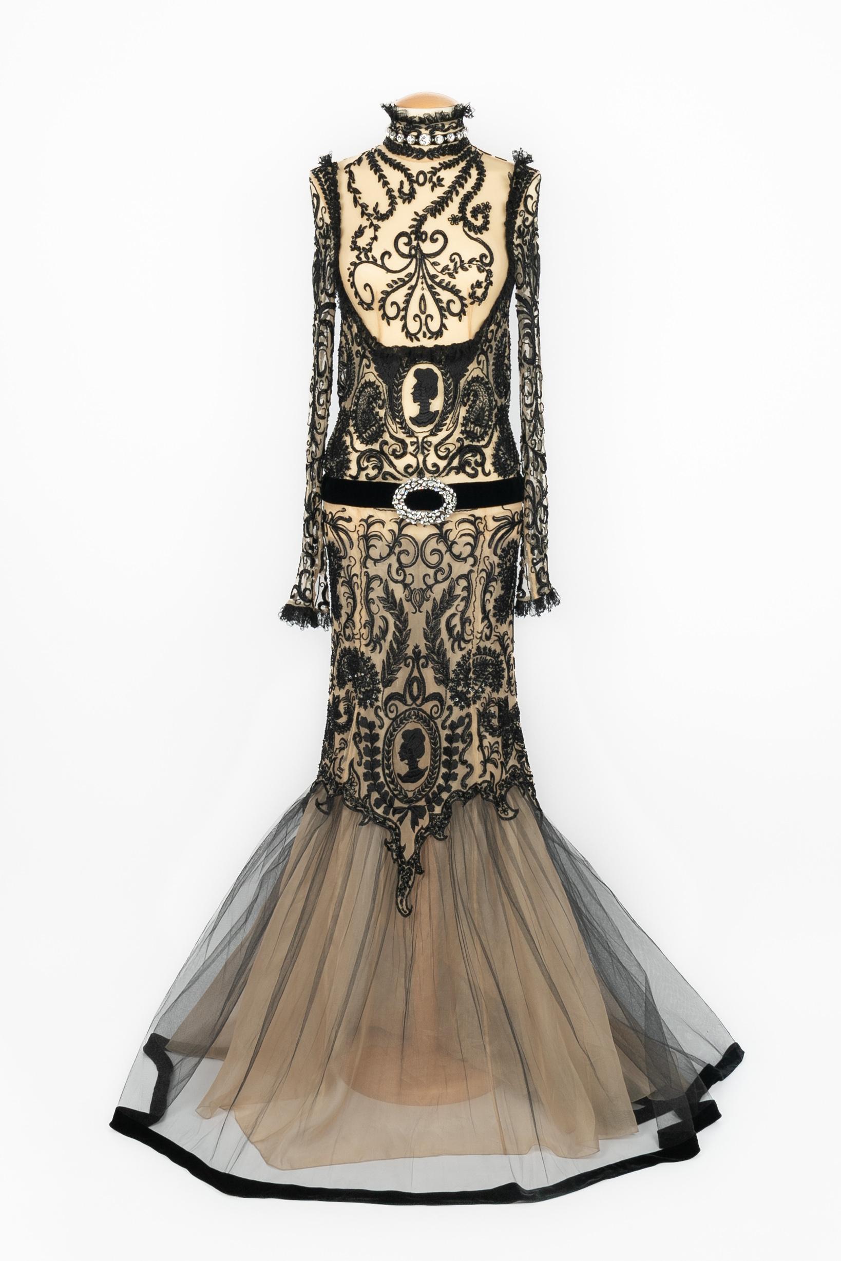 Jean-Louis Scherrer - Abito in tulle beige interamente ricamato con perle e fili neri, di ispirazione edoardiana. Per accentuare il punto vita, una finta cintura di velluto con strass. Bottoni in metallo argentato con strass e pizzo nero. Non è