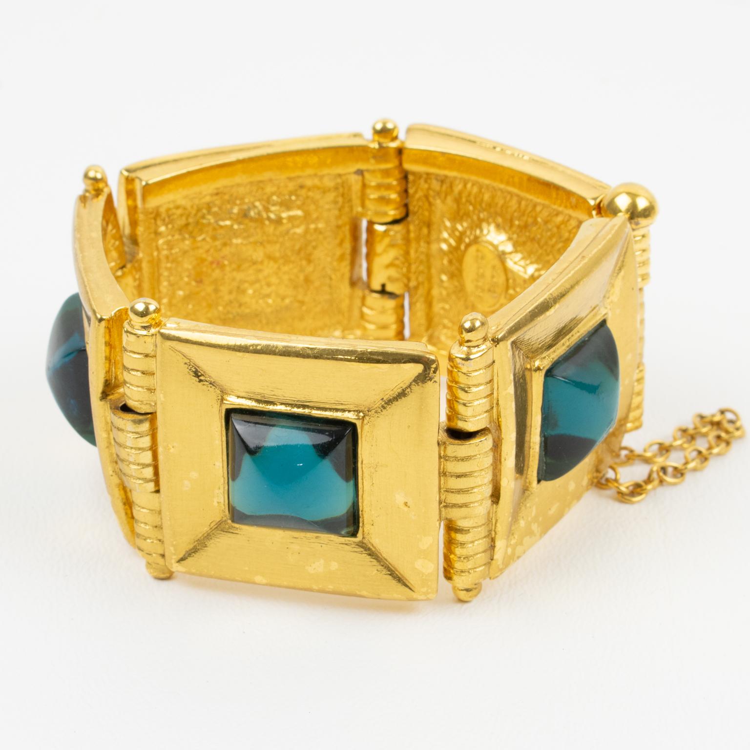 Dieses schöne Jean Louis Scherrer Paris Gliederarmband hat eine geometrische Form aus glänzendem Metall, die mit türkisblauen Cabochons aus Harz verziert ist. Die Sicherheitskette und der Verschluss sind in einwandfreiem Zustand. Das Armband ist auf