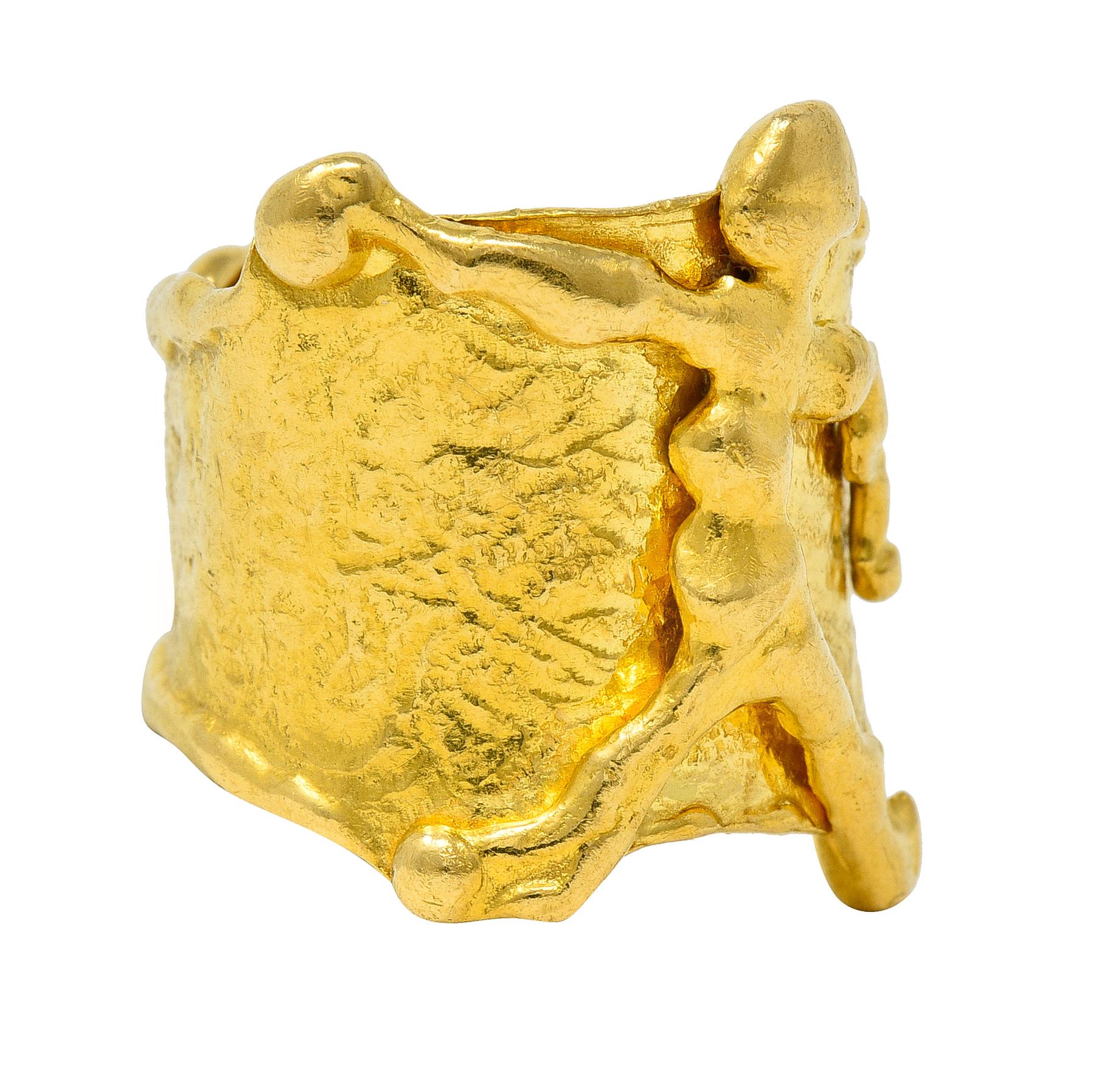 Designed as a tapered wide band ring with globular edges and organic texture throughout. Centering a raised stylized stick figure with raised arm. Organic and matched in globular style. Stamped 22k for 22 karat gold. With maker's mark for Jean