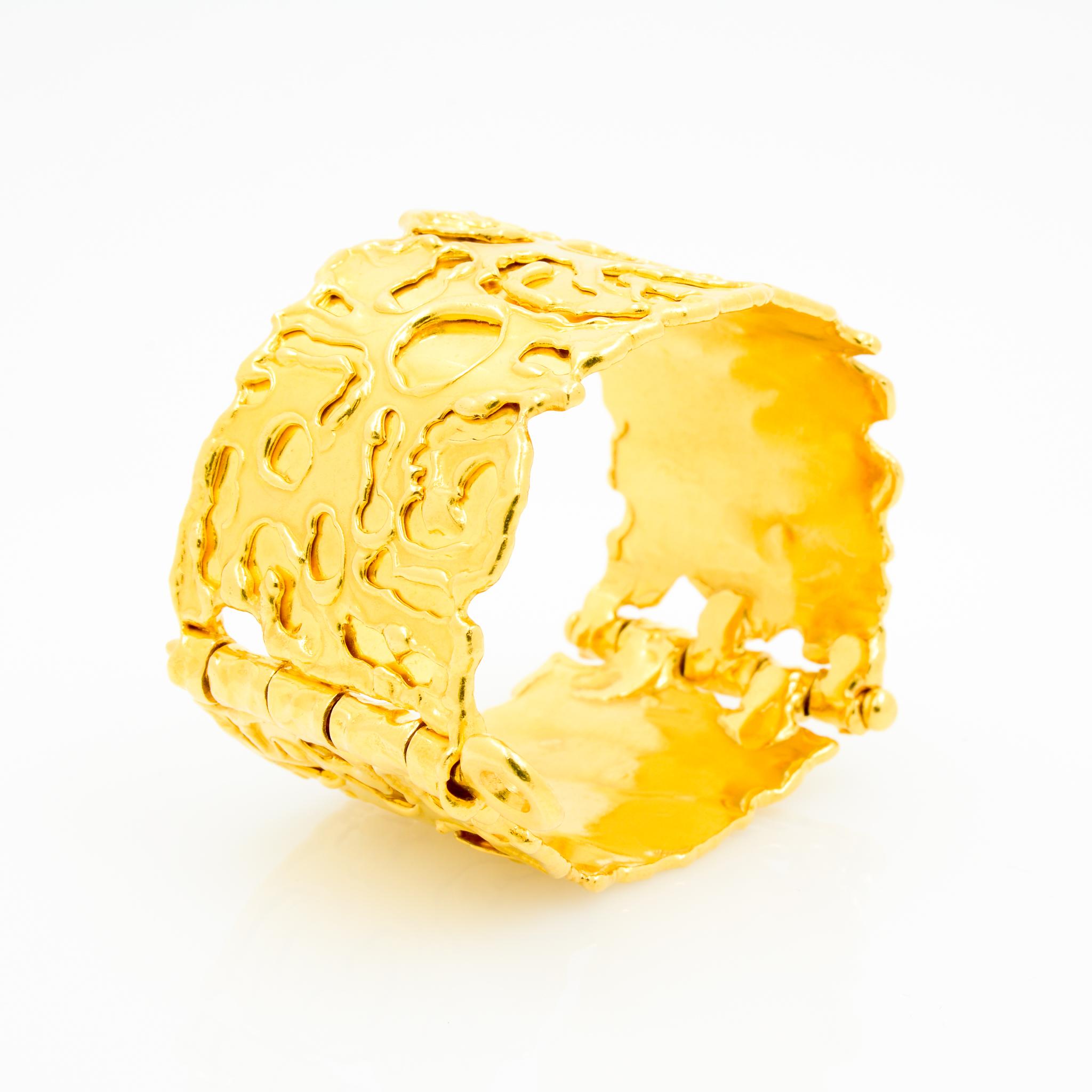 By designer Jean Mahie, this pin clasp hinged bangle is crafted from 22 karat yellow gold, with Mahie's signature primitive organic designs adorning the surface. This limited edition cuff bracelet is on of the widest versions of this style measuring