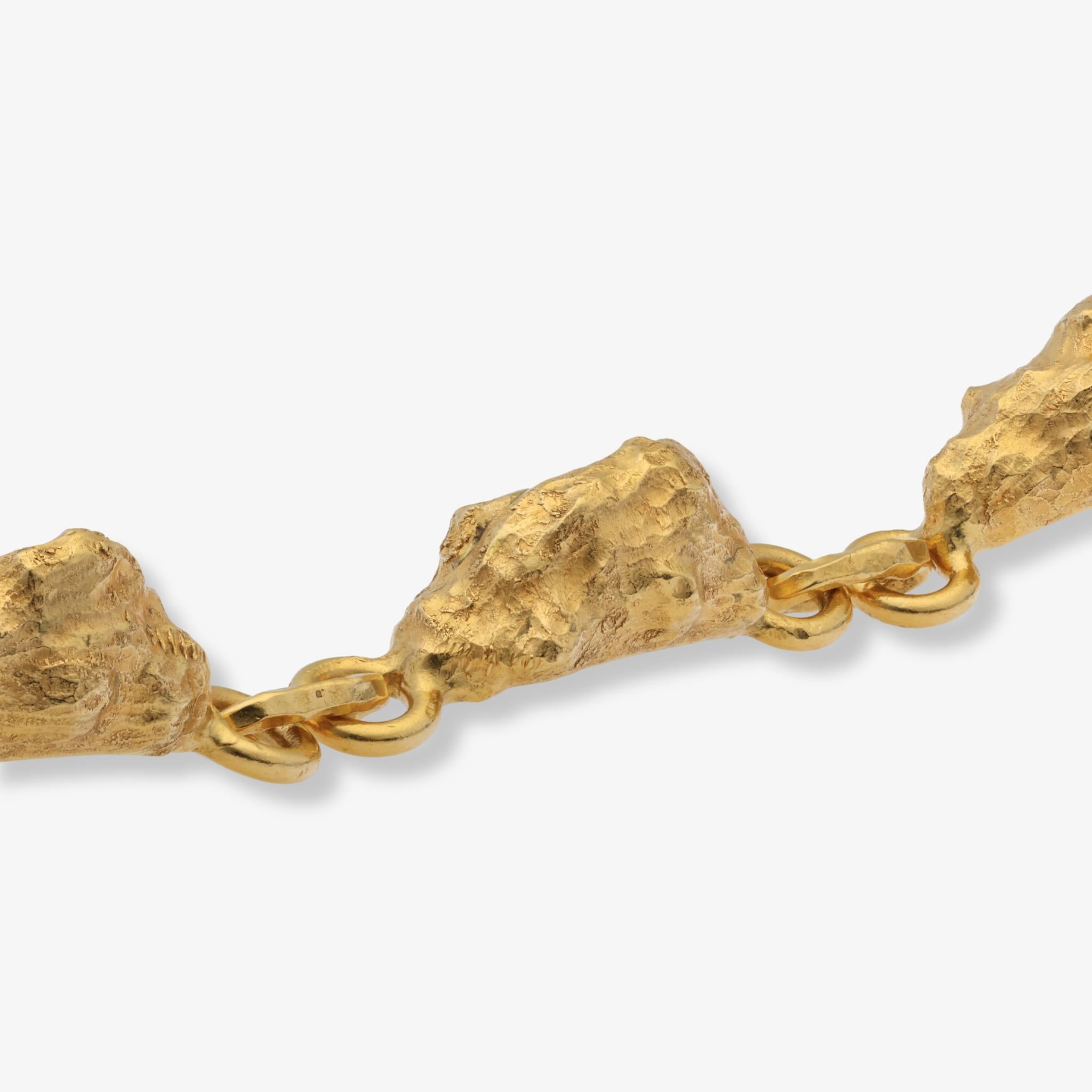 Un bracelet Jean Mahie fait à la main, composé de maillons sculpturaux texturés en or 22 carats.

Ce bracelet Jean Mahie capture l'esthétique distinctive de l'artiste, forgée à la main, définie par des surfaces richement texturées et des formes