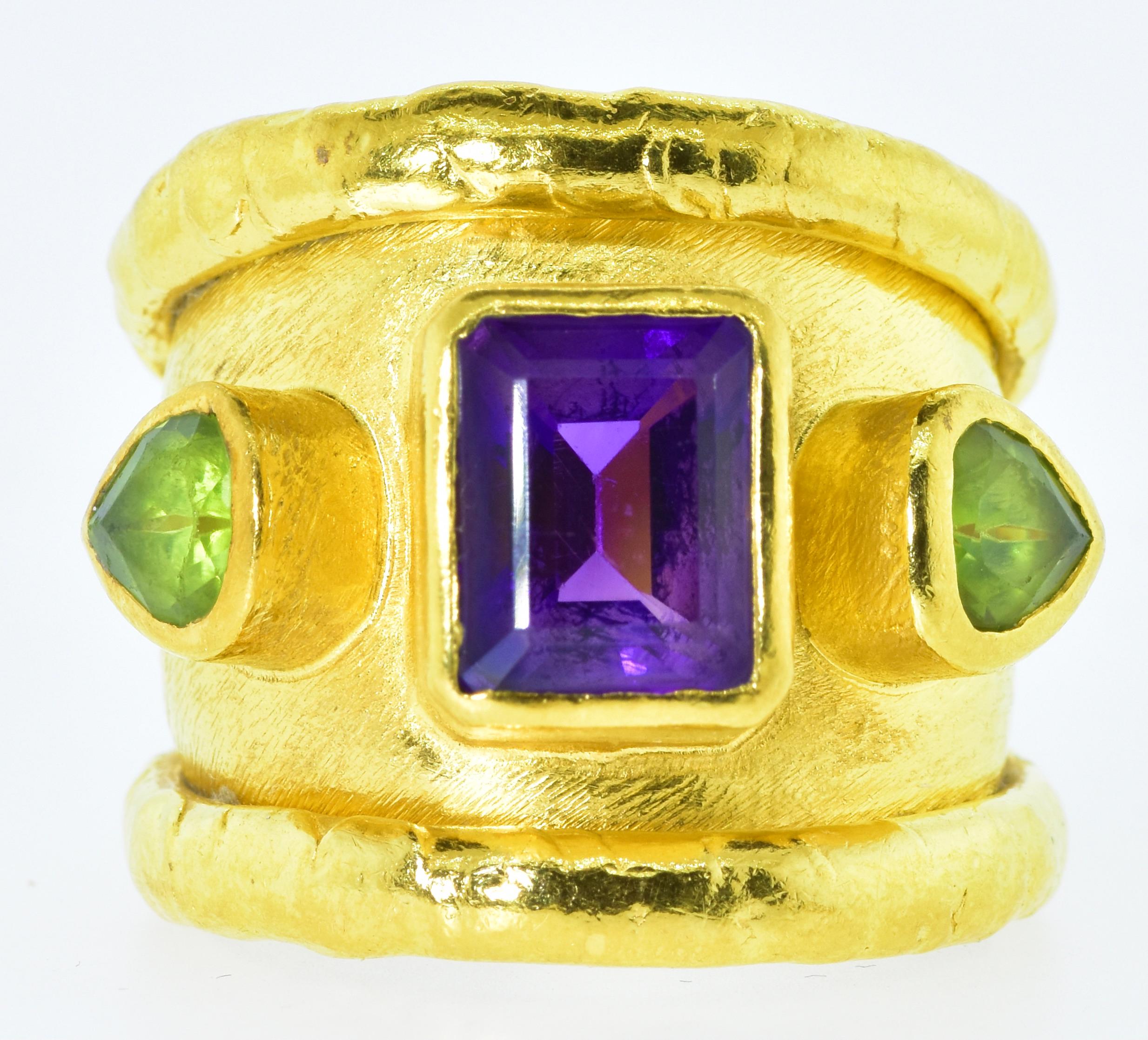 Jean Mahie 22K gold ring centering a fine emerald cut amethyst and two pear cut peridots.  This ring is signed with the JM signature for the atelier Jean Mahie in Paris.  This is a large ring with hand hammered 22K gold.   This ring can be sized as