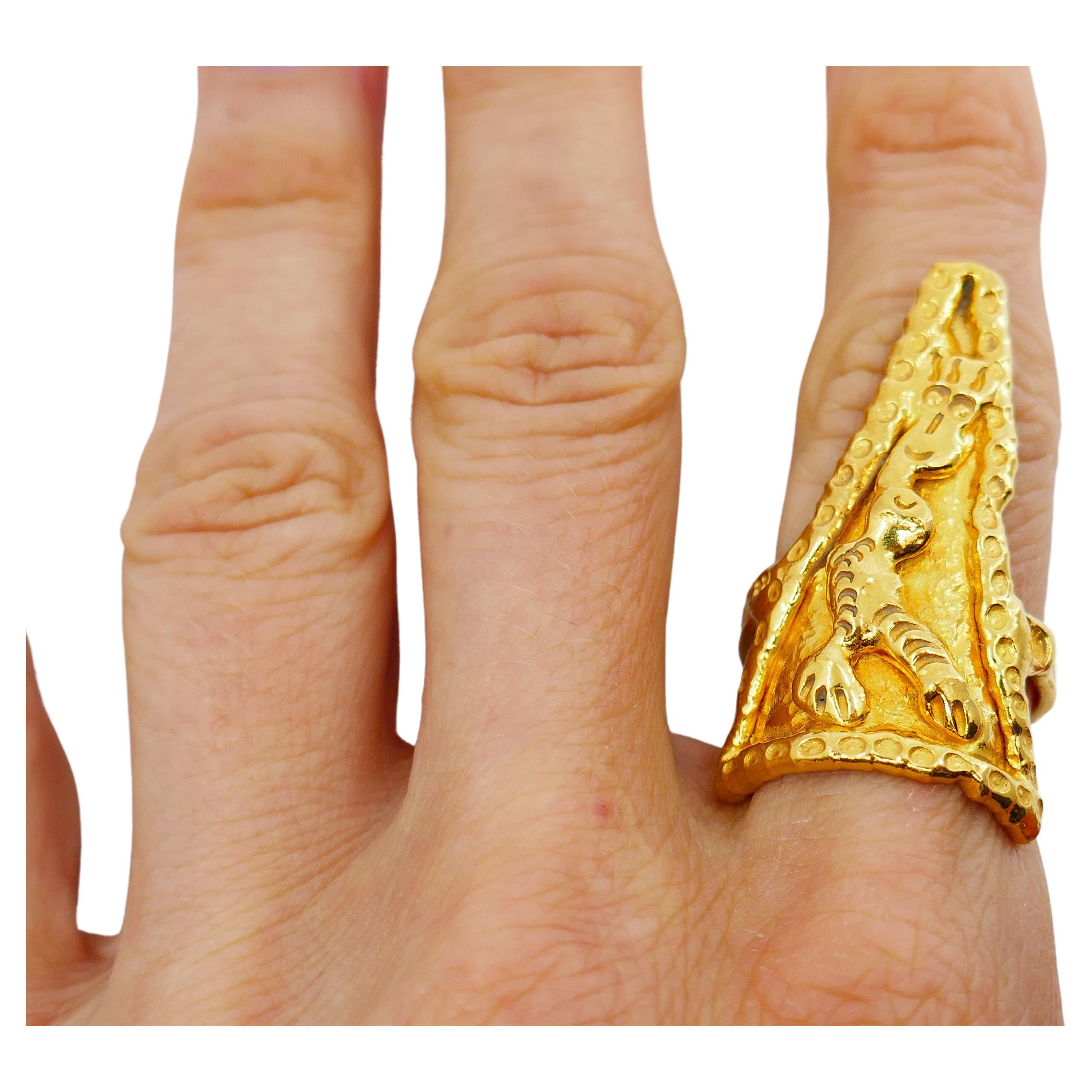 A unique Jean Mahie triangular ring made of 22k gold.
The ring has an abstract design resembles a figure with a smiling face. The figure is framed by a dotted gold frame. The shank is also dotted with little circles. All these details along with the