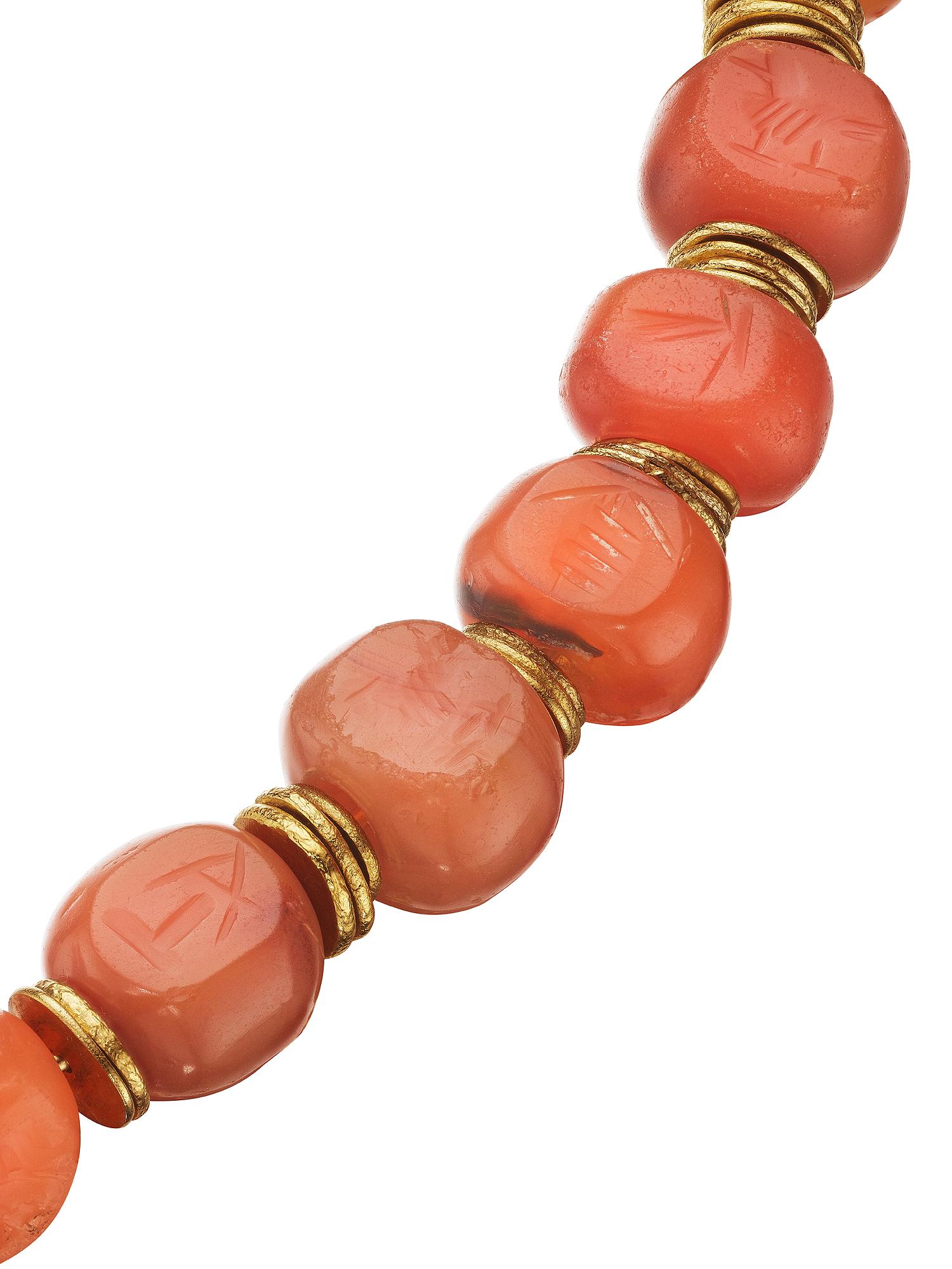 Designed by Jean Mahie using ancient carved earth tone Cornelian beads, circa 200 BC-500 AD, and 22 karat gold accents, this vintage choker necklace has both a timeless and modern vibe.  With 25 Mesopotamia beads carved with seals representing a