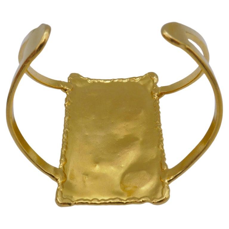 Bracelet manchette large et rectangulaire de Jean Mahie en or 18 carats. Il s'agit d'une pièce remarquable qui peut être portée avec n'importe quelle tenue.
Le bracelet en or est constitué d'une plaque présentant un motif abstrait et deux barres