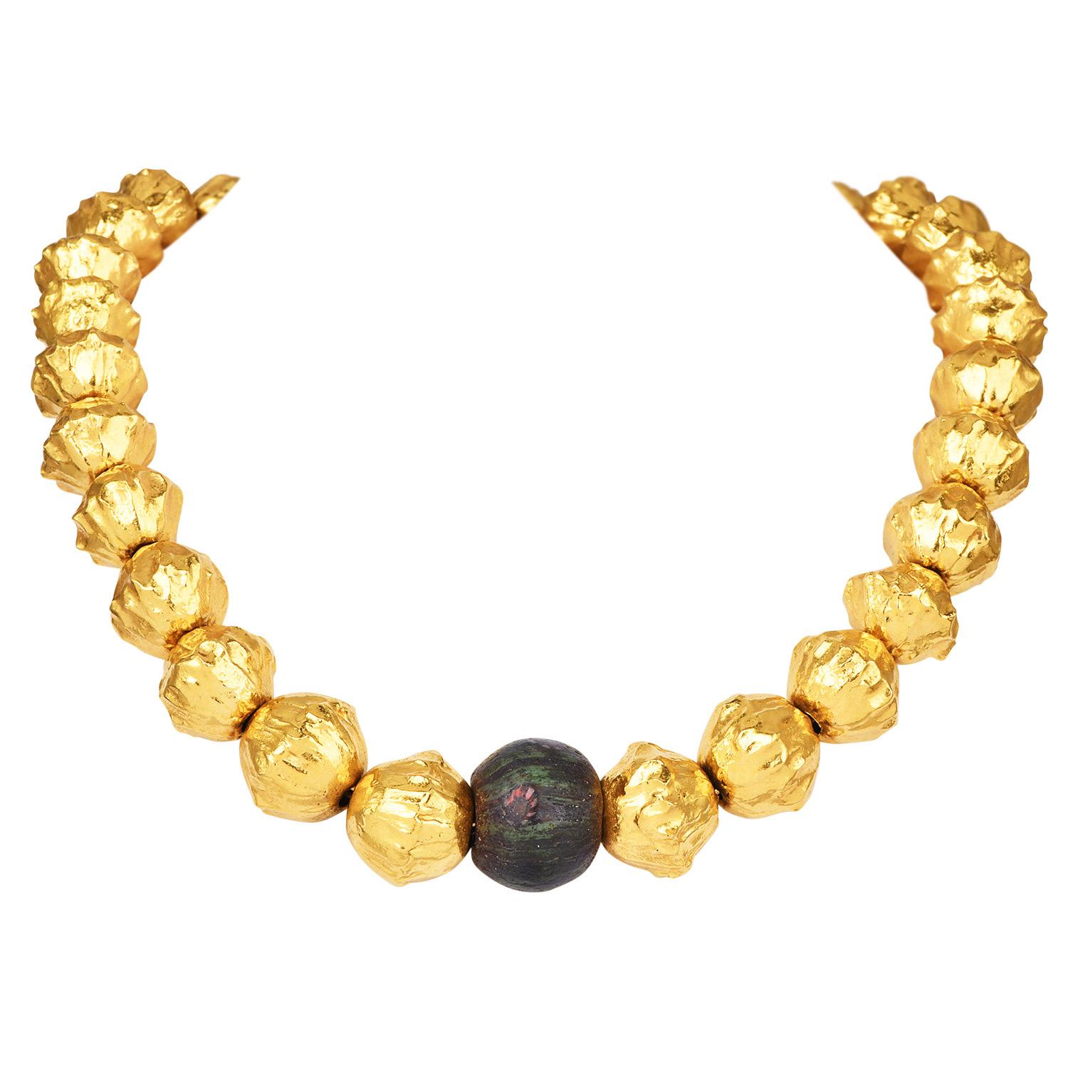 Questo prezioso gioiello in oro giallo 22 carati di Jean Mahie presenta perline dalla texture decisa che vanno da 14 a 19 mm, centrate da un'impressionante pietra rotonda di 20 mm. Il design incarna la maestria di Jean Mahie, ispirata a motivi
