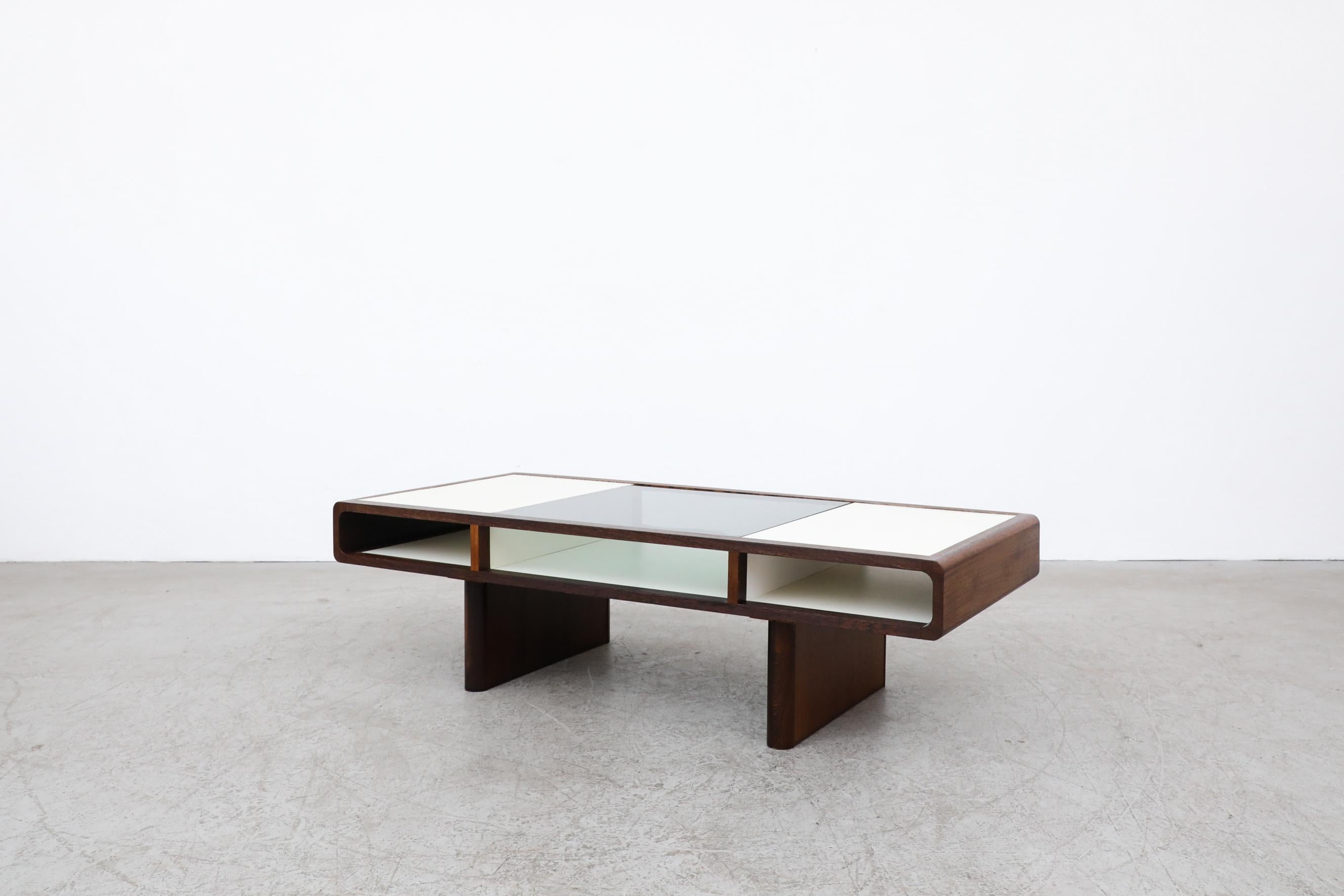 This Jean Maneval style wenge and white coffee table features three storage compartments, ideal for magazines and books. The center of the table is smoked glass. It is in original condition with a few minor scratches and no structural damage. The