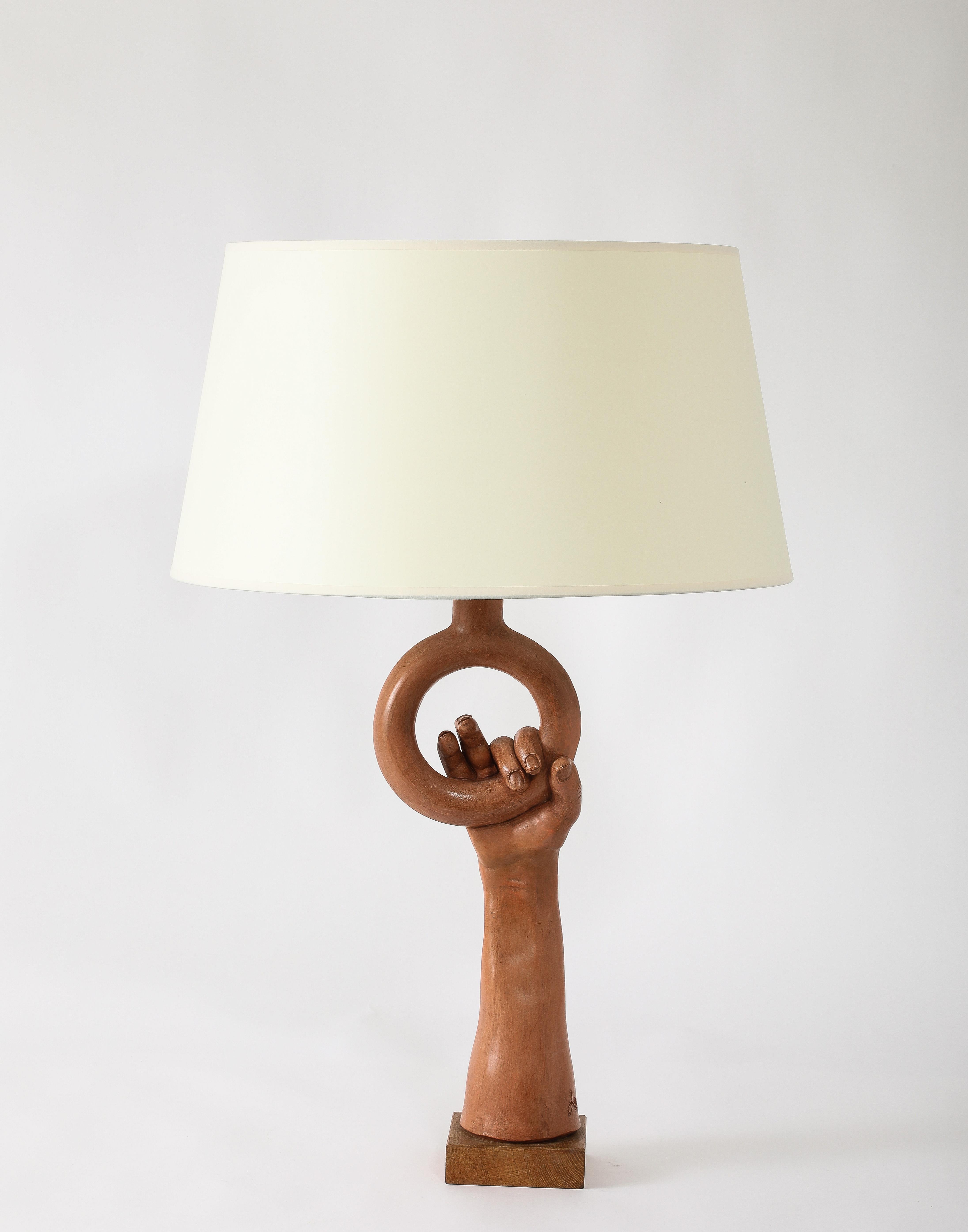 One of Jean Marais most striking lamp designs, a life-size arm holding a ring in glazed terra-cotta. Signed.