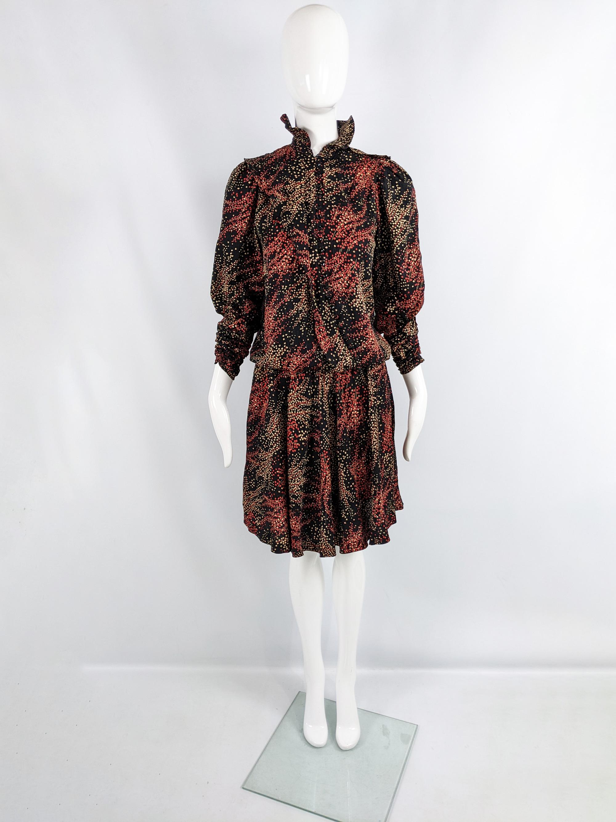 Un increíble vestido vintage para mujer de los años 80 de los lujosos diseñadores de moda británicos Jean & Martin Pallant. En un tejido de pura seda negra con un estampado abstracto de flores rojas y crema. Tiene una cintura elástica con caída, que