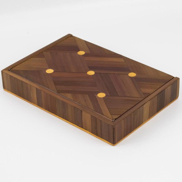Il s'agit d'une jolie boîte à couvercle décorative en marqueterie de paille Art déco dont le design est attribué à Jean Michel Frank (1895 - 1941). La forme rectangulaire présente un design géométrique raffiné, et l'intérieur est doublé de liège. Il