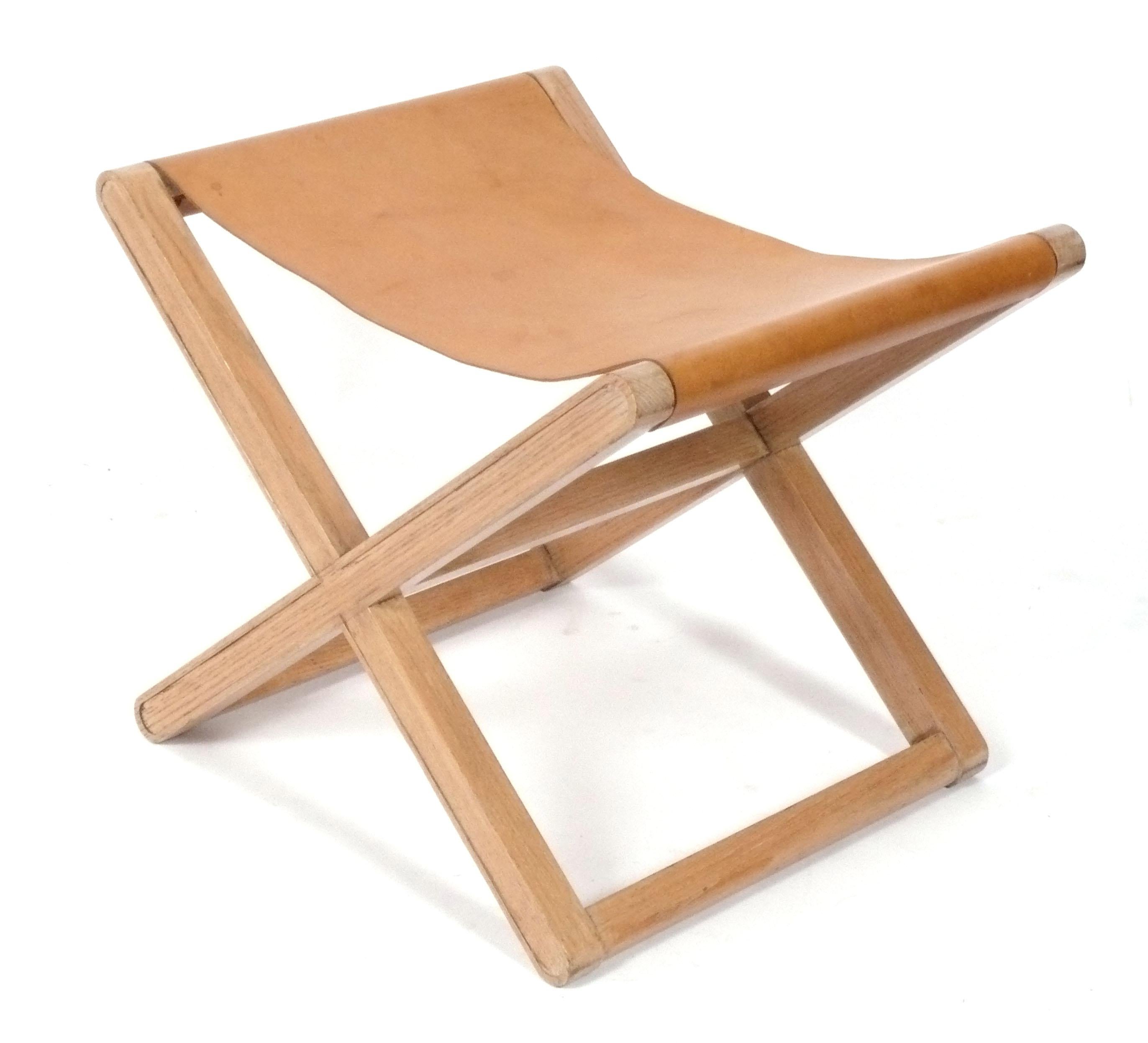 Tabouret sculptural en cuir à base en X, conçu à l'origine par Jean Michel Frank dans les années 1930, cet exemplaire date probablement des années 1980. Elle a conservé sa chaude patine d'origine, avec quelques taches sur la bandoulière en cuir. 