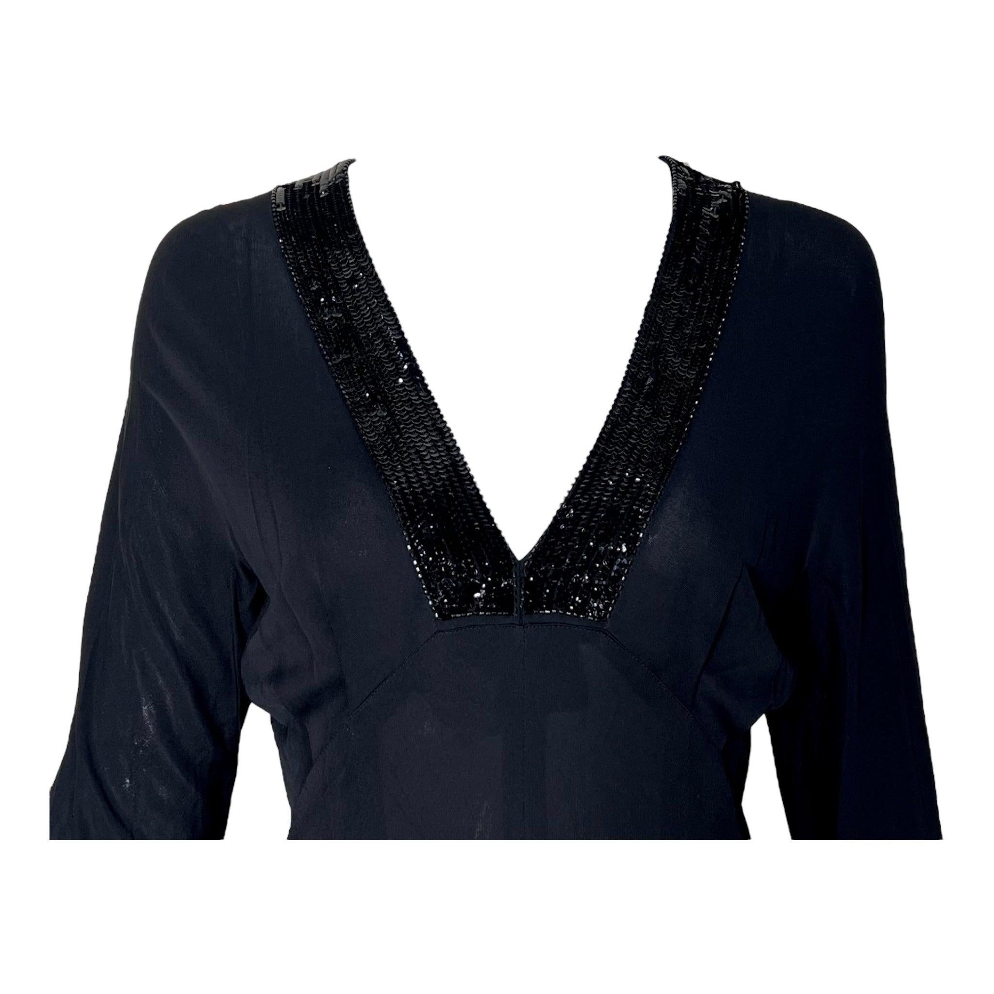 Robe fluide et sexy des années 70, signée Jean Muir, la créatrice anglaise préférée des amateurs. Jersey de rayonne noir mat avec détails de paillettes noires ponctuant le profond décolleté en V. Paillettes noires assorties aux poignets. Silhouette