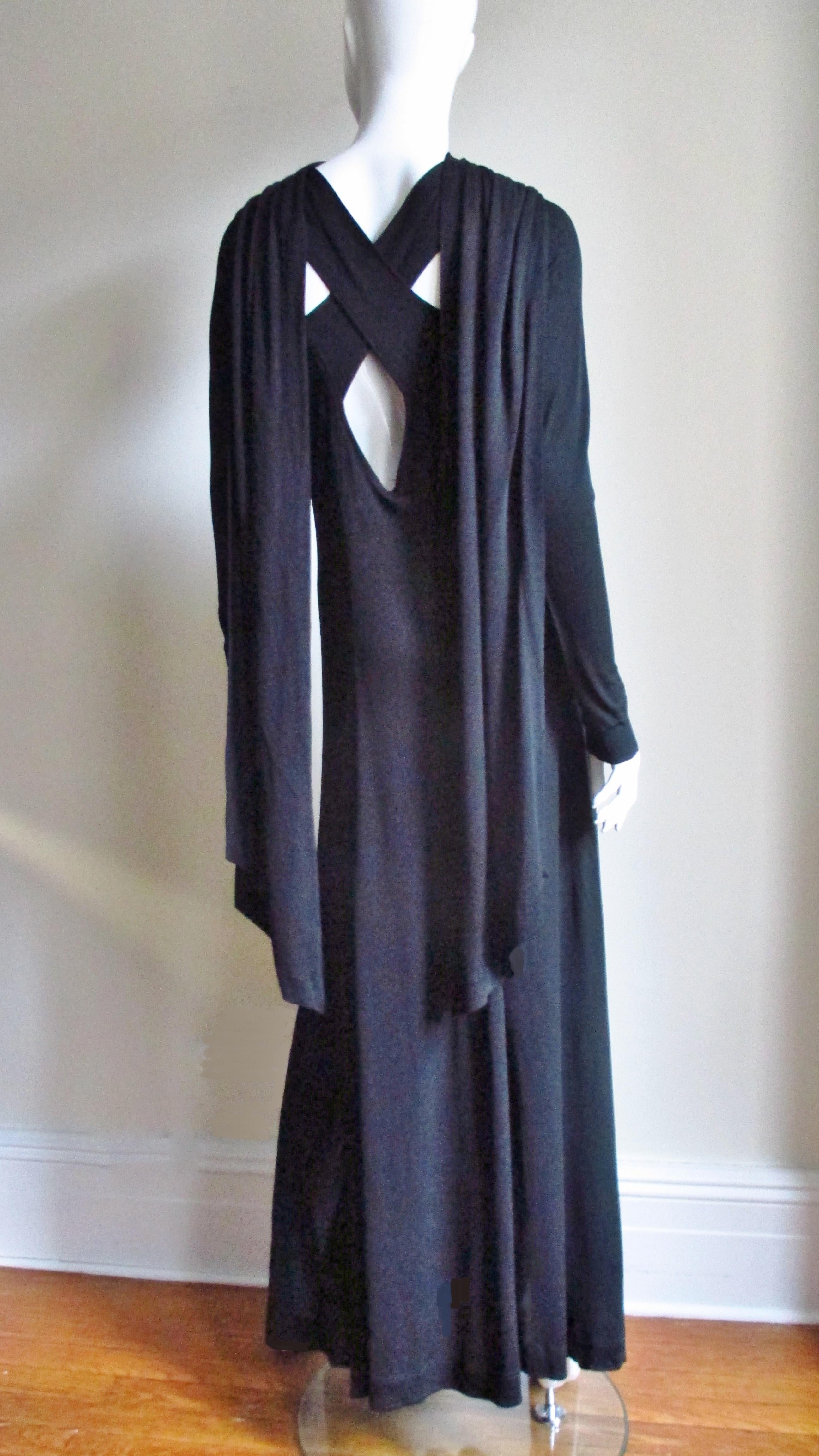 A fabulous black jersey full length dress gown from legendary British designer Jean Muir. This dress has lots of detail- cut outs at the shoulders, upper and mid back with shoulder draping down each side at the back. There is seaming creating a