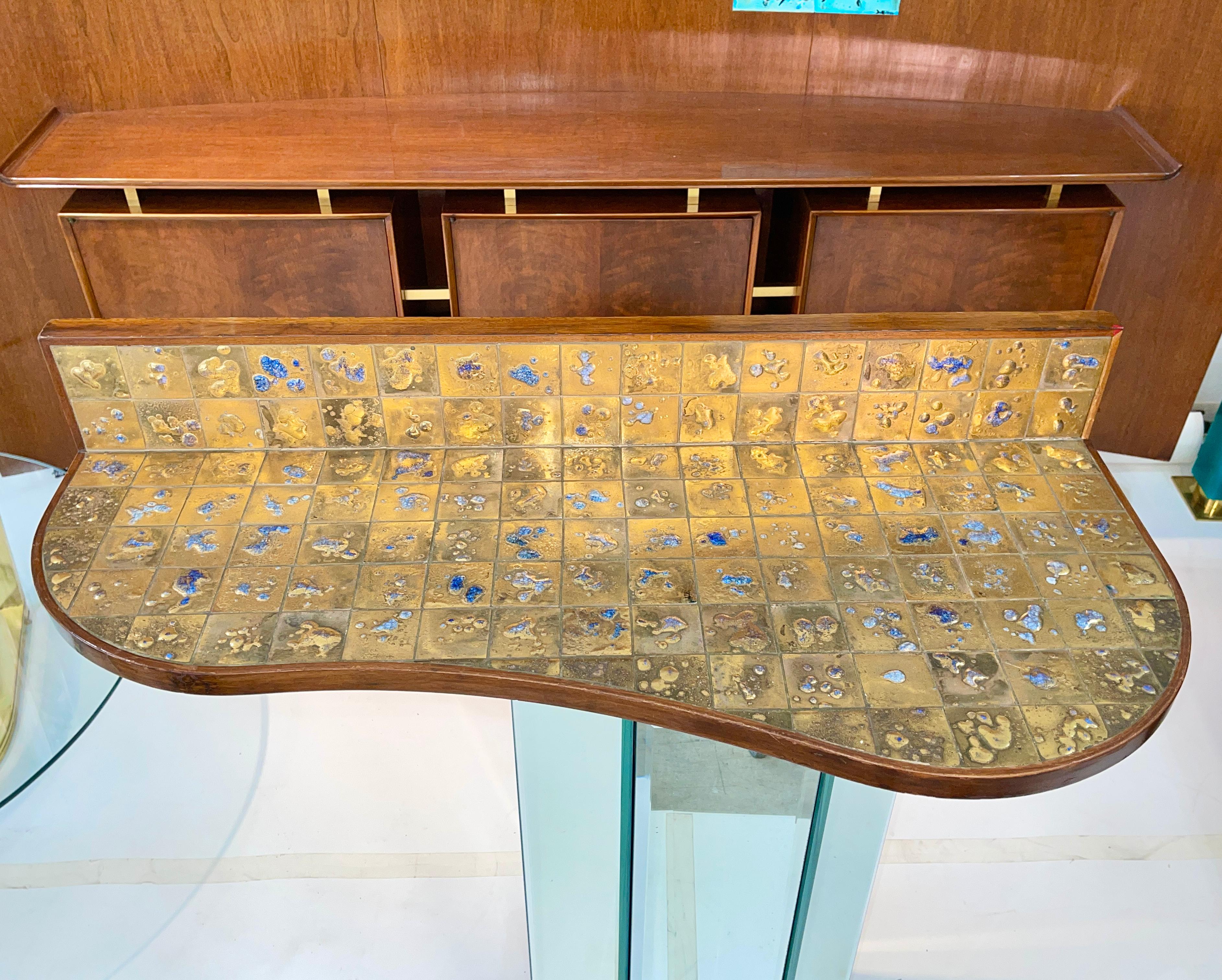 Organically shaped wall-mounted floating console table shelf in walnut trim and set with ~130 individual art tiles created by ceramicist Jean Nison (1922-2015).
This work was custom made for the 90 Riverside Drive apartment of Jacques and Alina