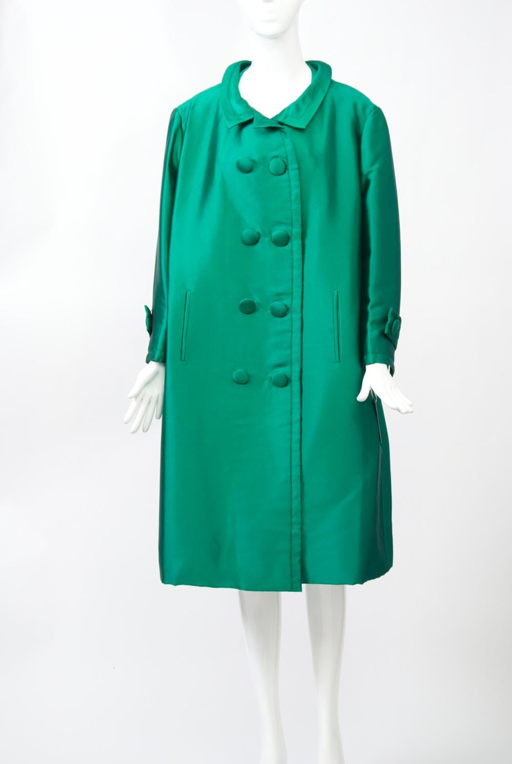 1960s emerald green silk evening coat by French couturier Jean Patou. Double breasted with self buttons and bound buttonholes, and small spread collar; topstitching throughout. Set-in, wrist-length sleeves with slit, tab and button. Slit pockets.