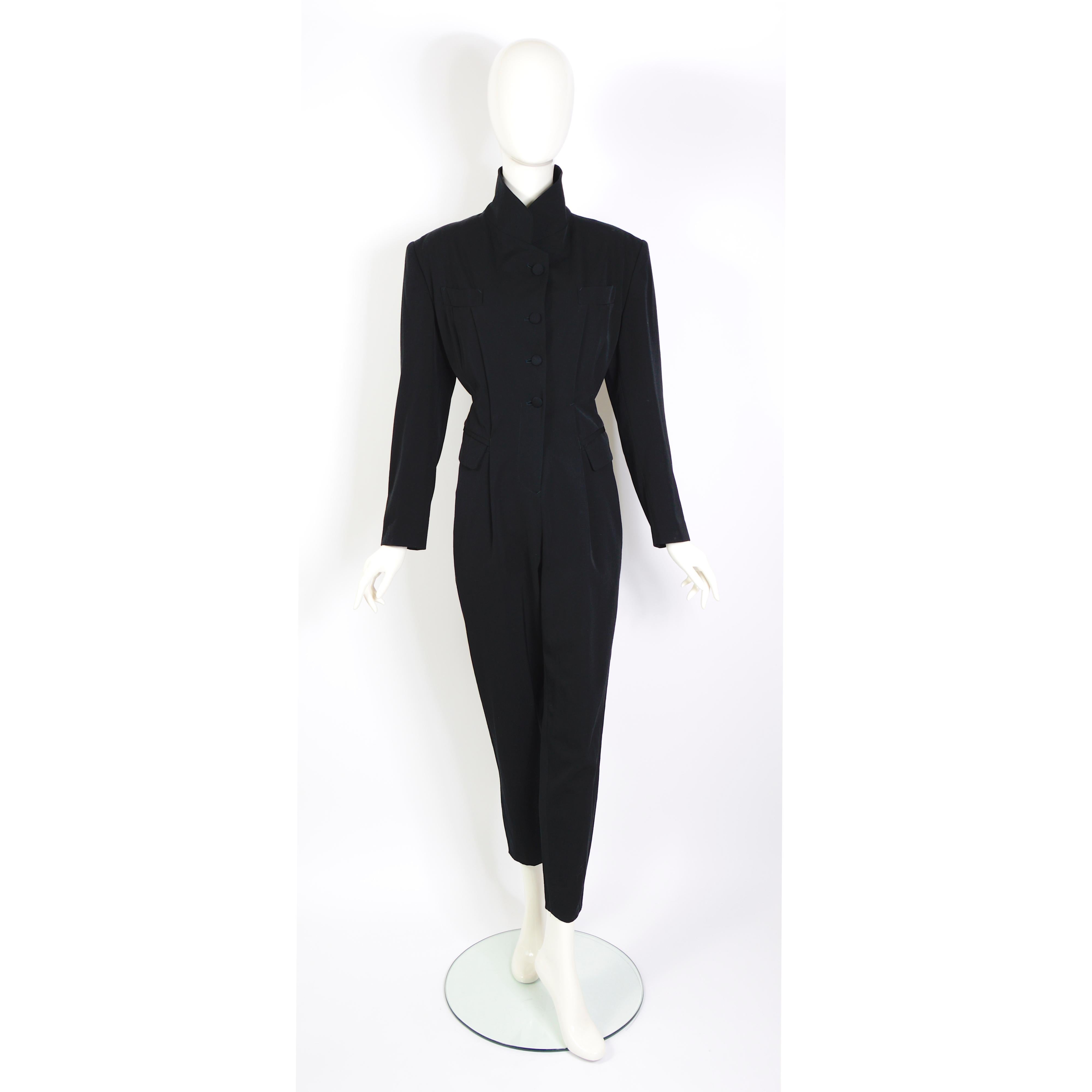 A wonderful and perfectly tailored vintage 1980s black jumpsuit by Jean-Paul Gaultier.
The front of the jumpsuit has three fabric-covered buttons and a zipper for closure. 
It features four pockets + a buttonhole in the lapel. The back of the