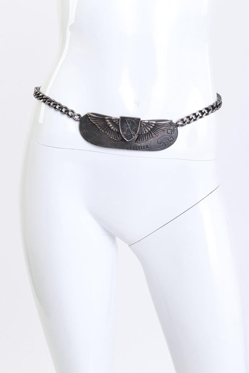 This hard-to-find 25th Anniversary Limited Edition belt by Jean Paul Gaultier is crafted in antique gunmetal with a substantial, weighty feel. The design features a curved center plate adorned with a winged crest, embossed profile, and scissor