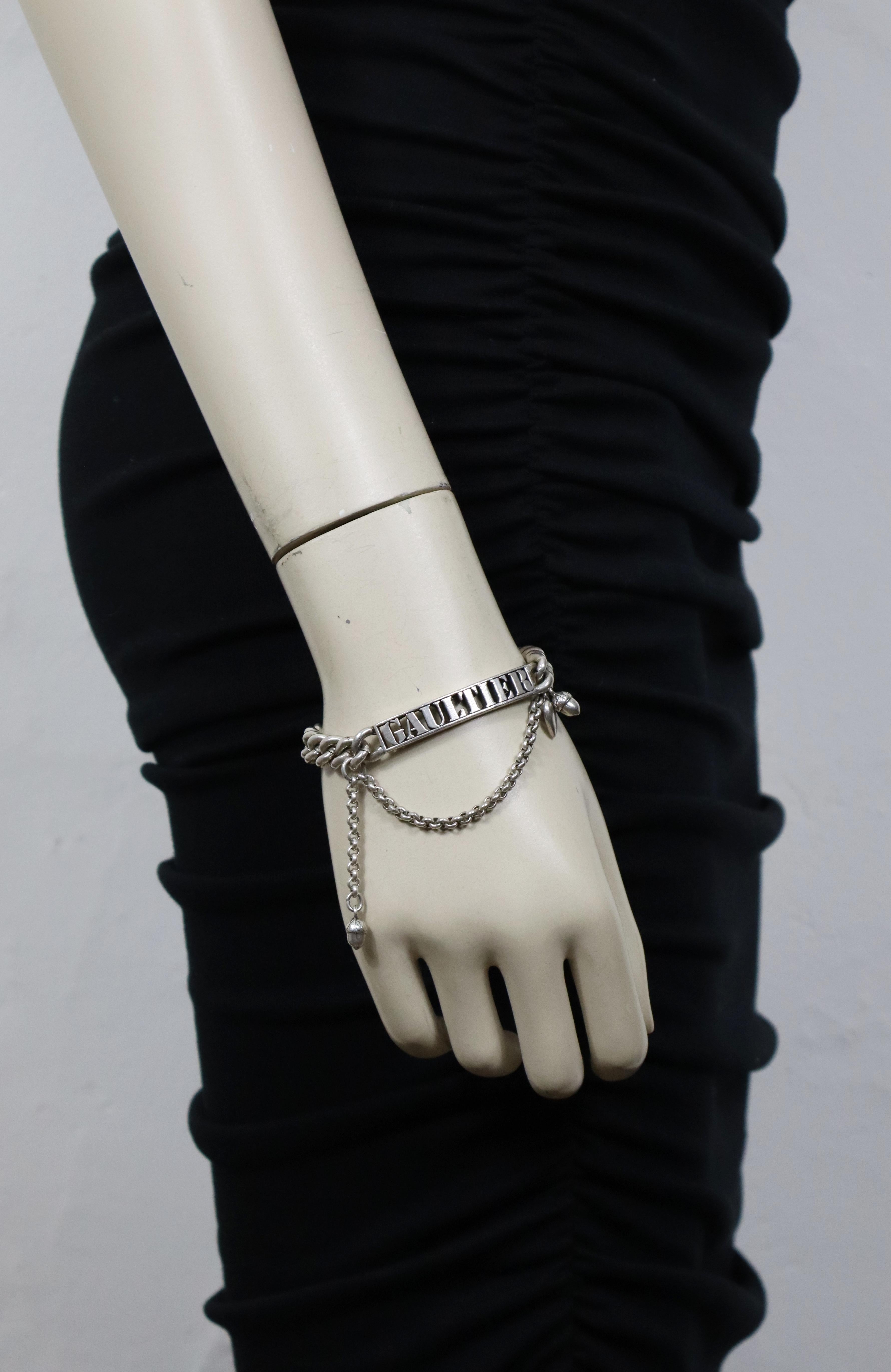 Bracciale a catena con cordoncino in argento anticato di Jean Paul Gaultier (attribuito a), con etichetta identificativa GAULTIER tagliata e charme.

Accessori in metallo color argento.
Patina anticata.

Chiusura con fibbia sicura.

Senza