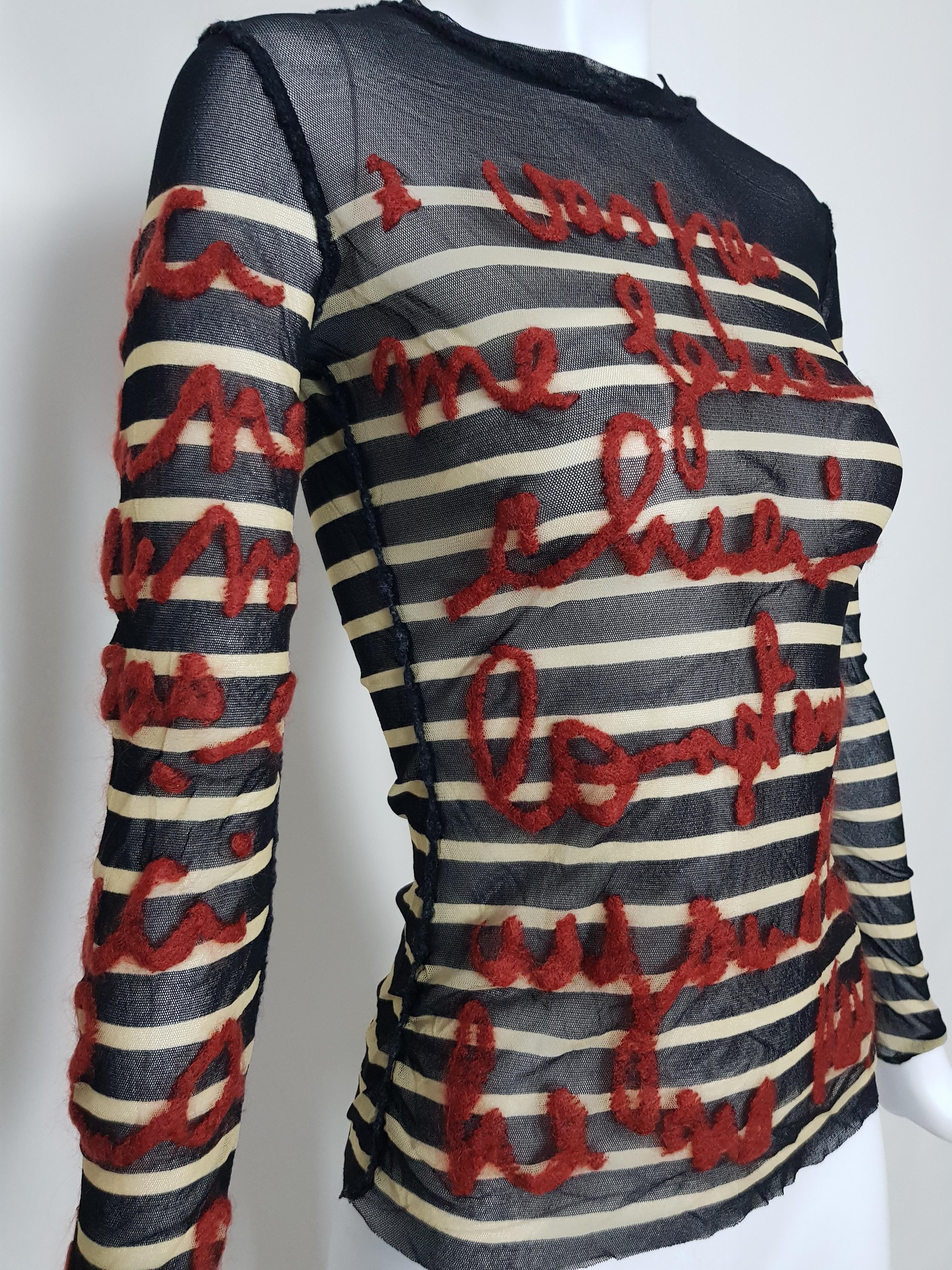 A wonderful and unique example of Jean Paul Gaultier's classic tattoo mesh sailor tops. 
The mesh has red wool French lettering stitched creating a look unique to it's self. 
No label, Gaultier's distinctive finishing.
Can fit S to M as fabric is