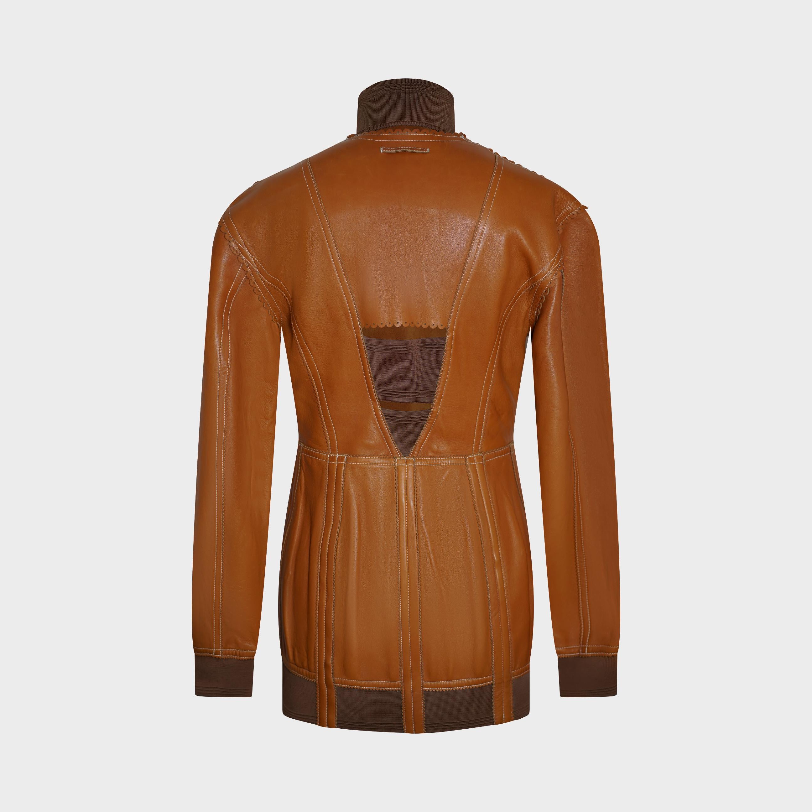 Issue de la Collection S/One 2004 de Jean Paul Gaultier (Look 7), cette veste en cuir d'agneau beige illustre le mélange de précision et de sensualité du créateur. Réalisée en cuir souple perforé, elle est dotée de panneaux en tricot extensible au