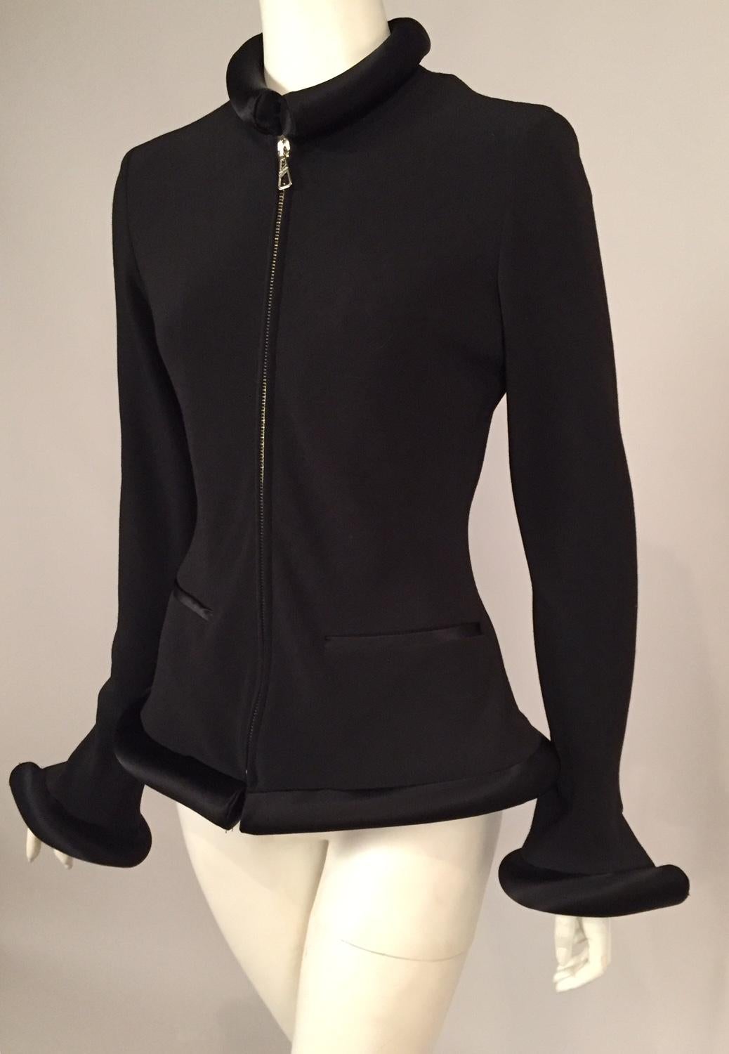 A spare but elegant black zip front jacket takes on a futuristic style with the addition of tubular padded black satin at the collar, cuffs and the hemline. The jacket fabric has some stretch insuring a flattering fit. It is marked a French size 40