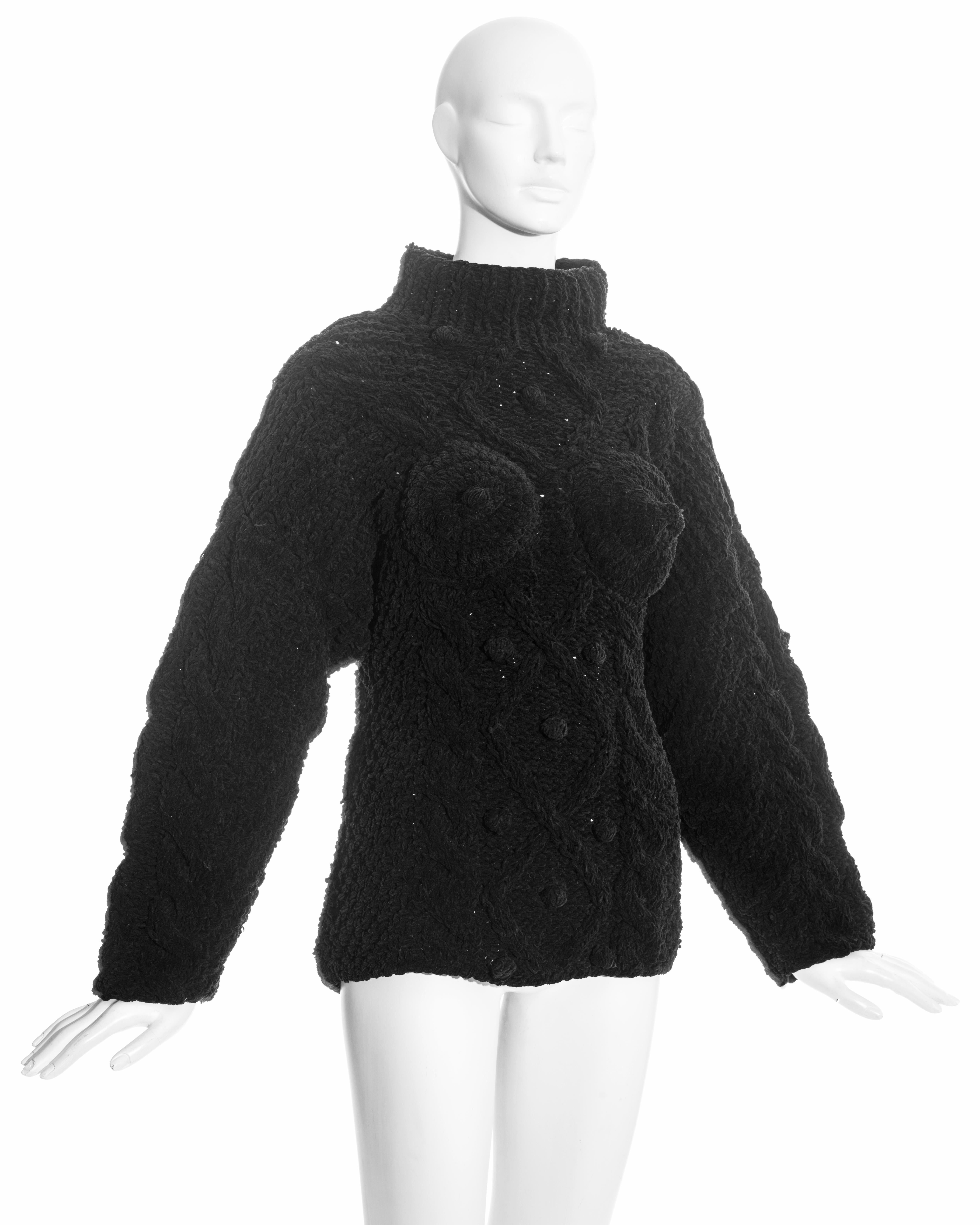 Jean Paul Gaultier schwarzer Chenille-Aran-Pullover mit breitem Stehkragen, Reißverschluss in der hinteren Mitte und den für Gaultier typischen konischen Brustpaneelen mit Nippeln. 

Herbst-Winter 1985